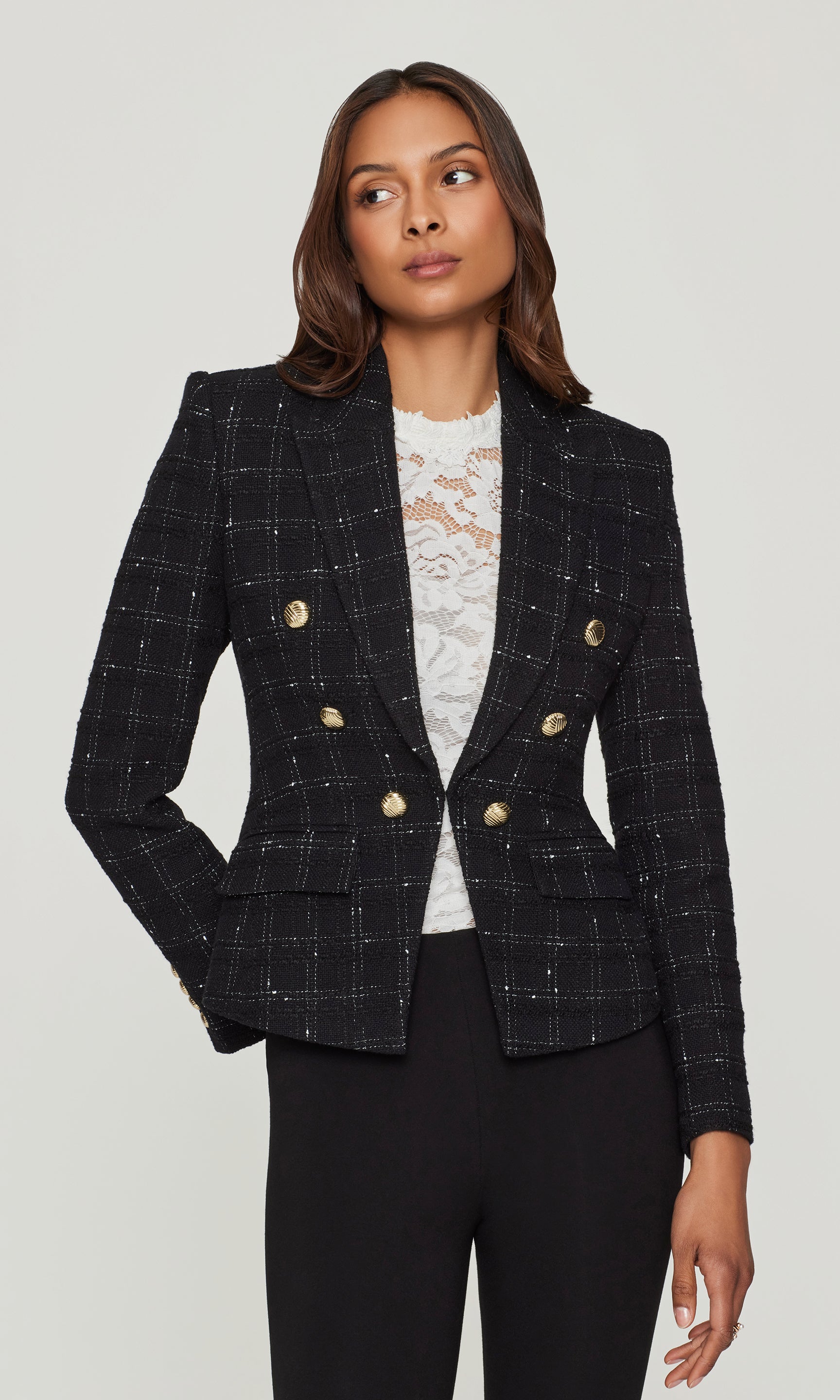 Woman wearing a black checkered blazer with gold buttons on a white background