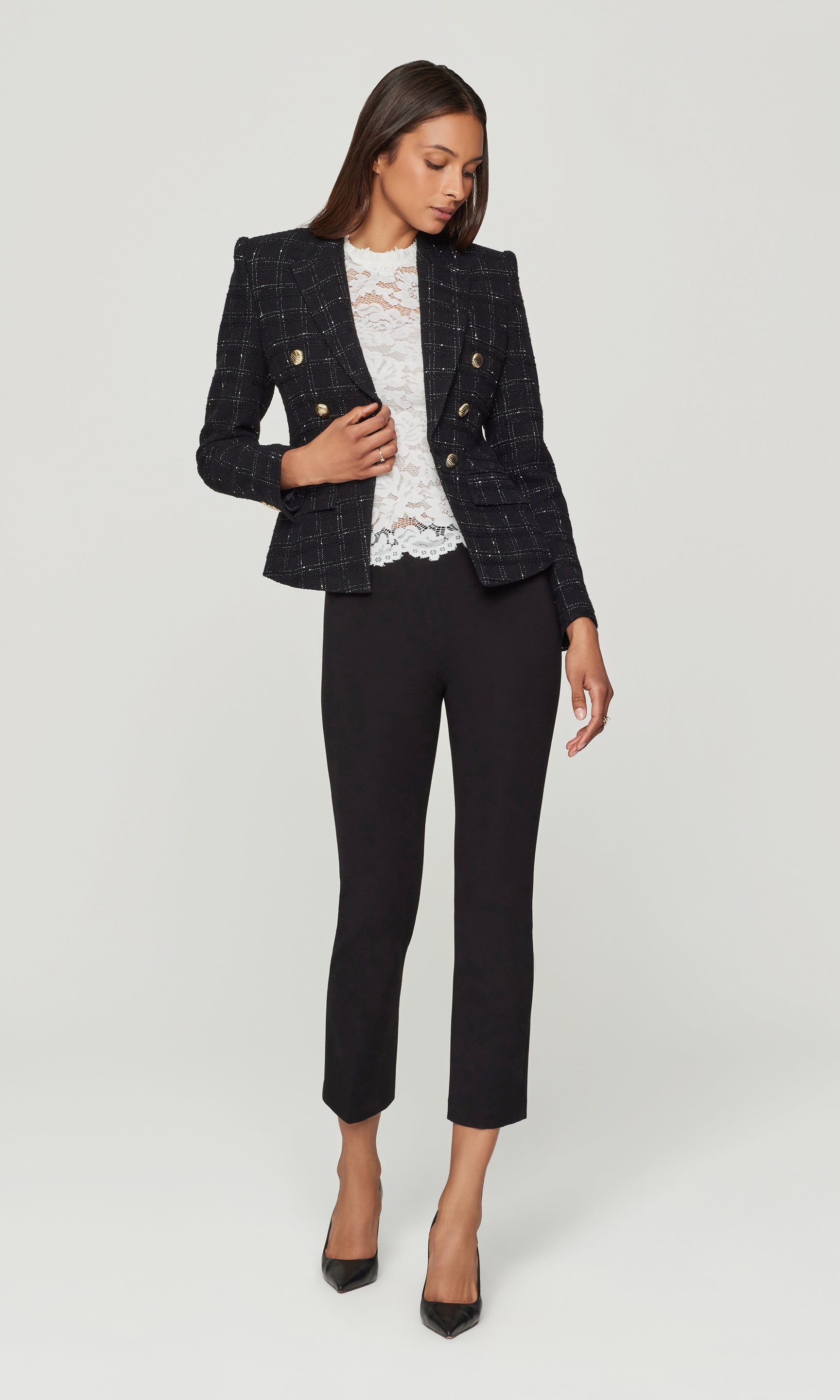 Woman wearing a black checkered blazer and black pants on a white background