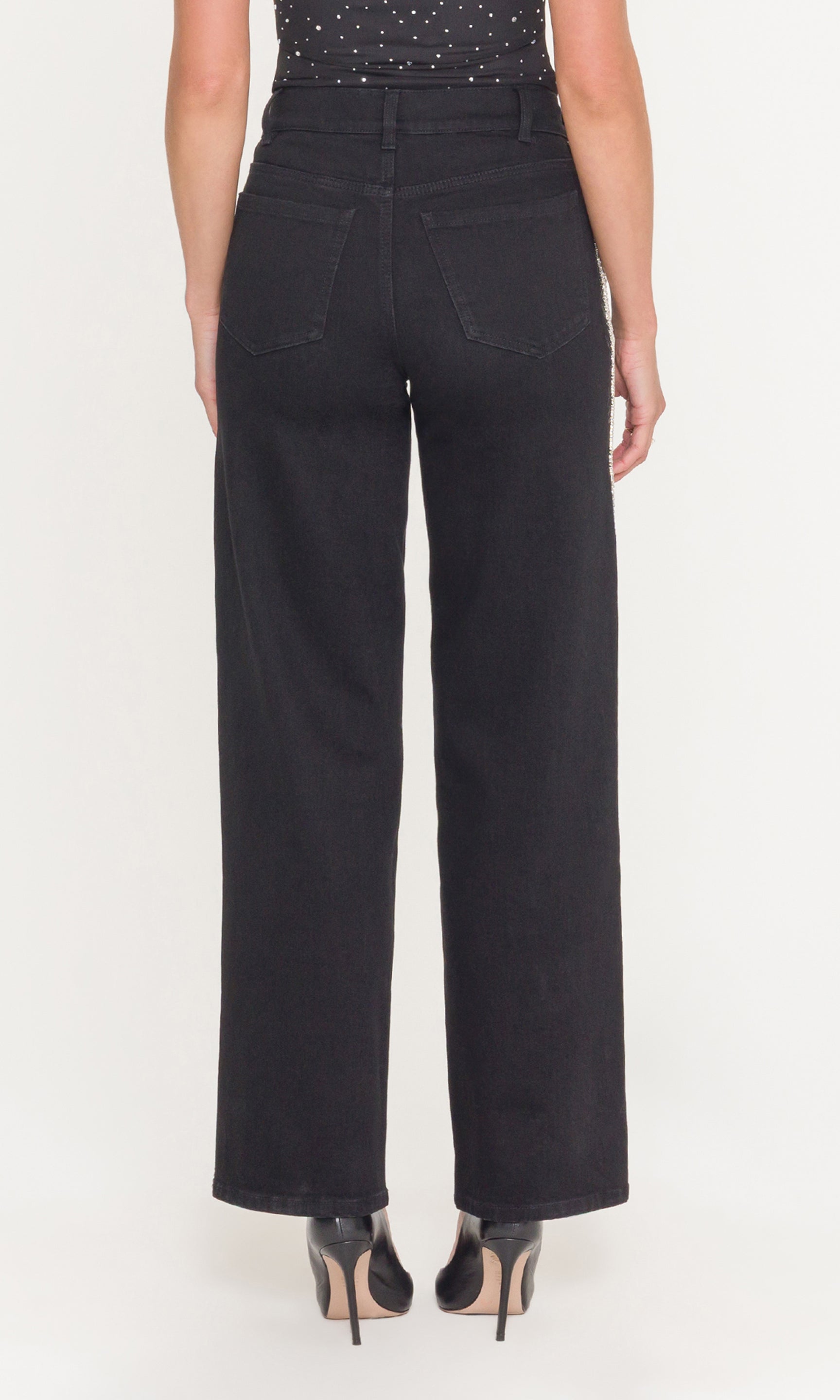 Back view of model wearing black jeans and black top on a white background