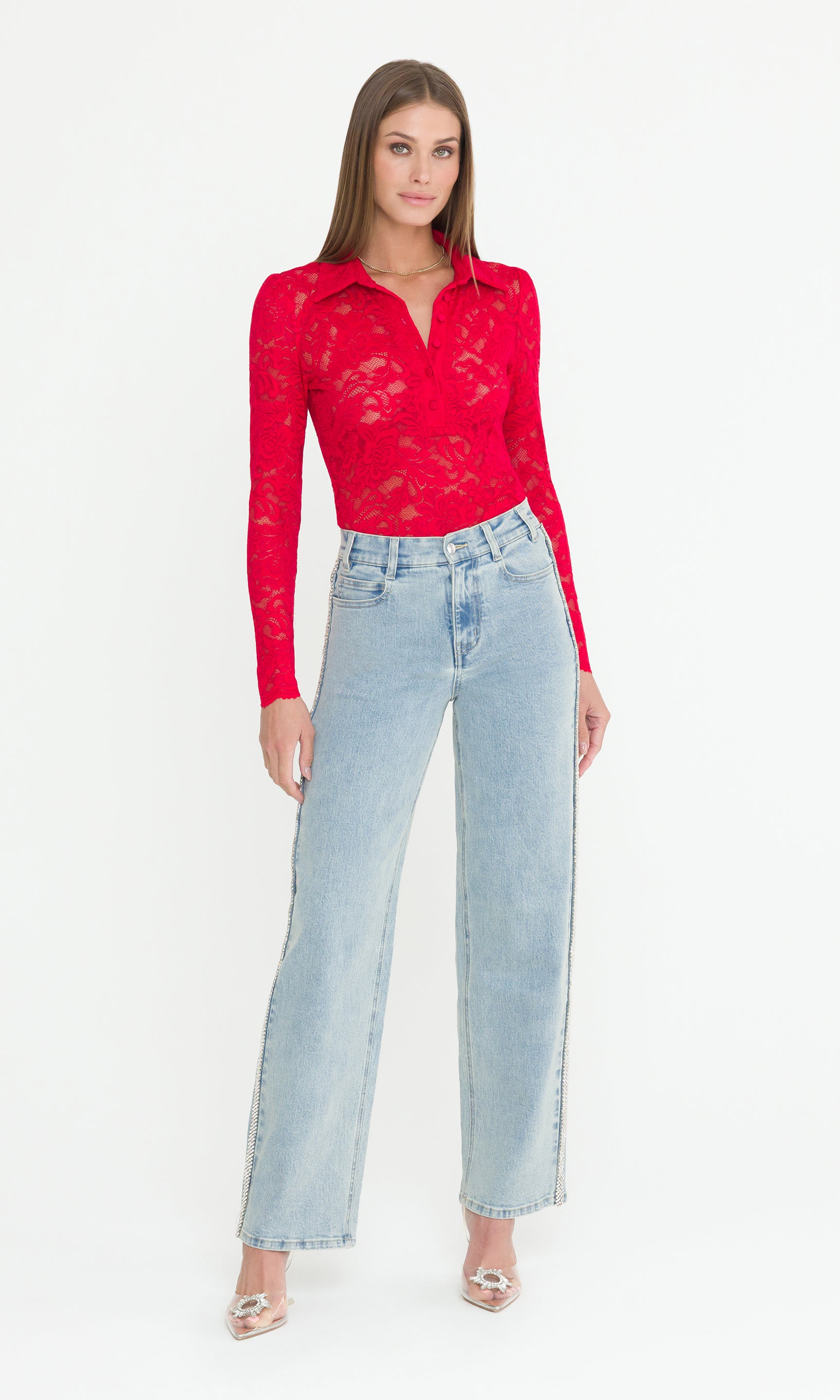 Full body image of model wearing a red lace top and light blue jeans on a white background
