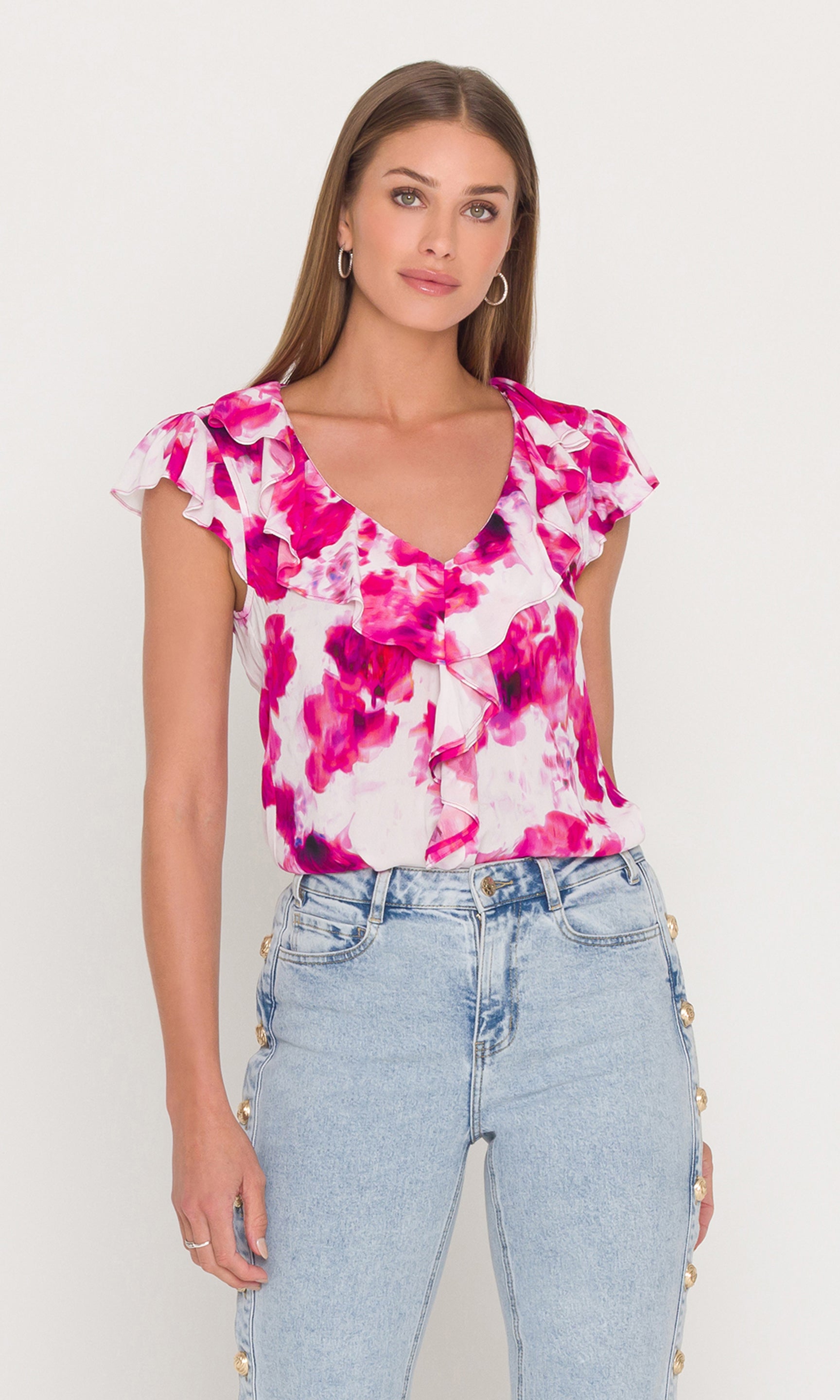 Woman wearing a floral top and jeans against a white background