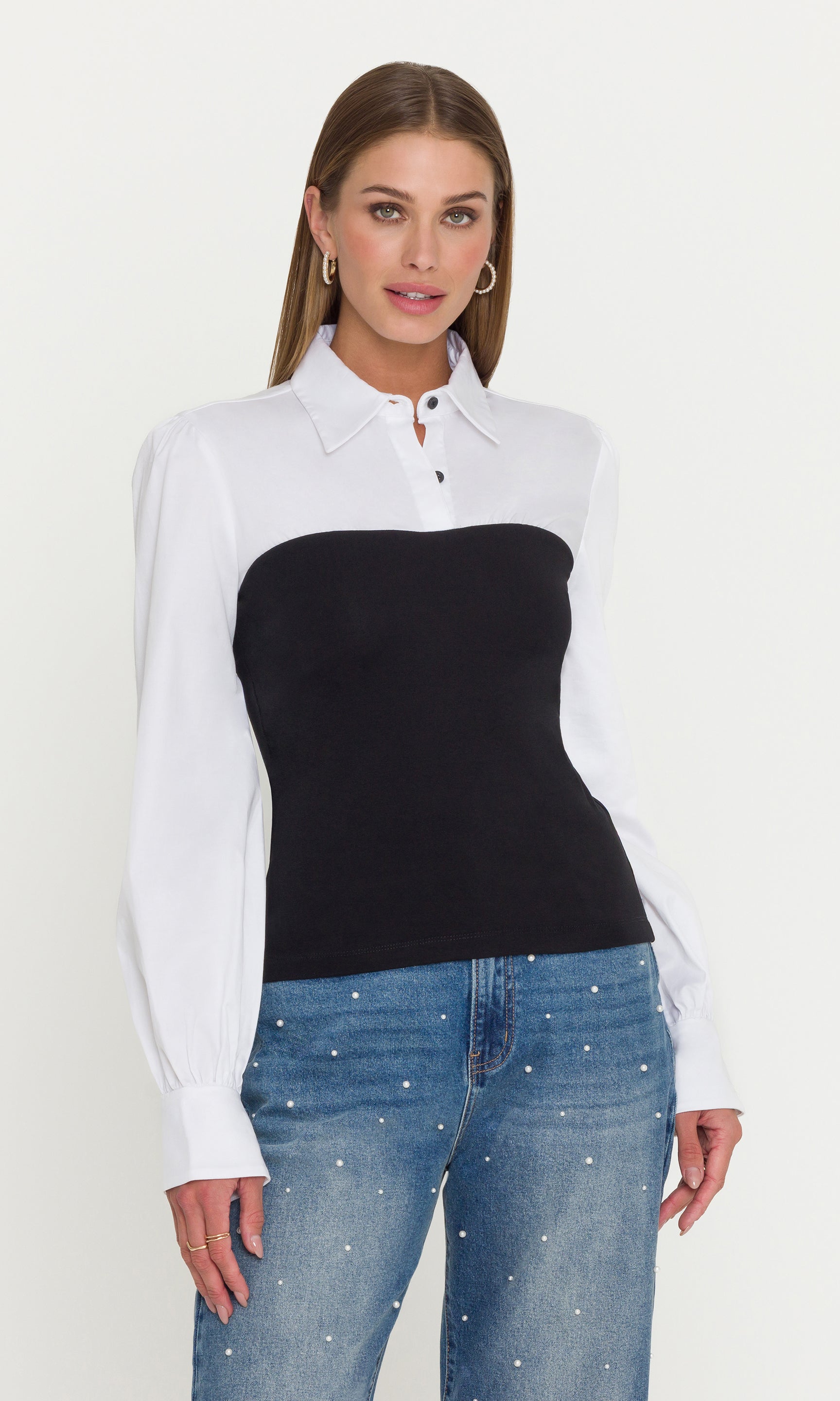 Woman wearing a white shirt with a black top and blue jeans on a white background