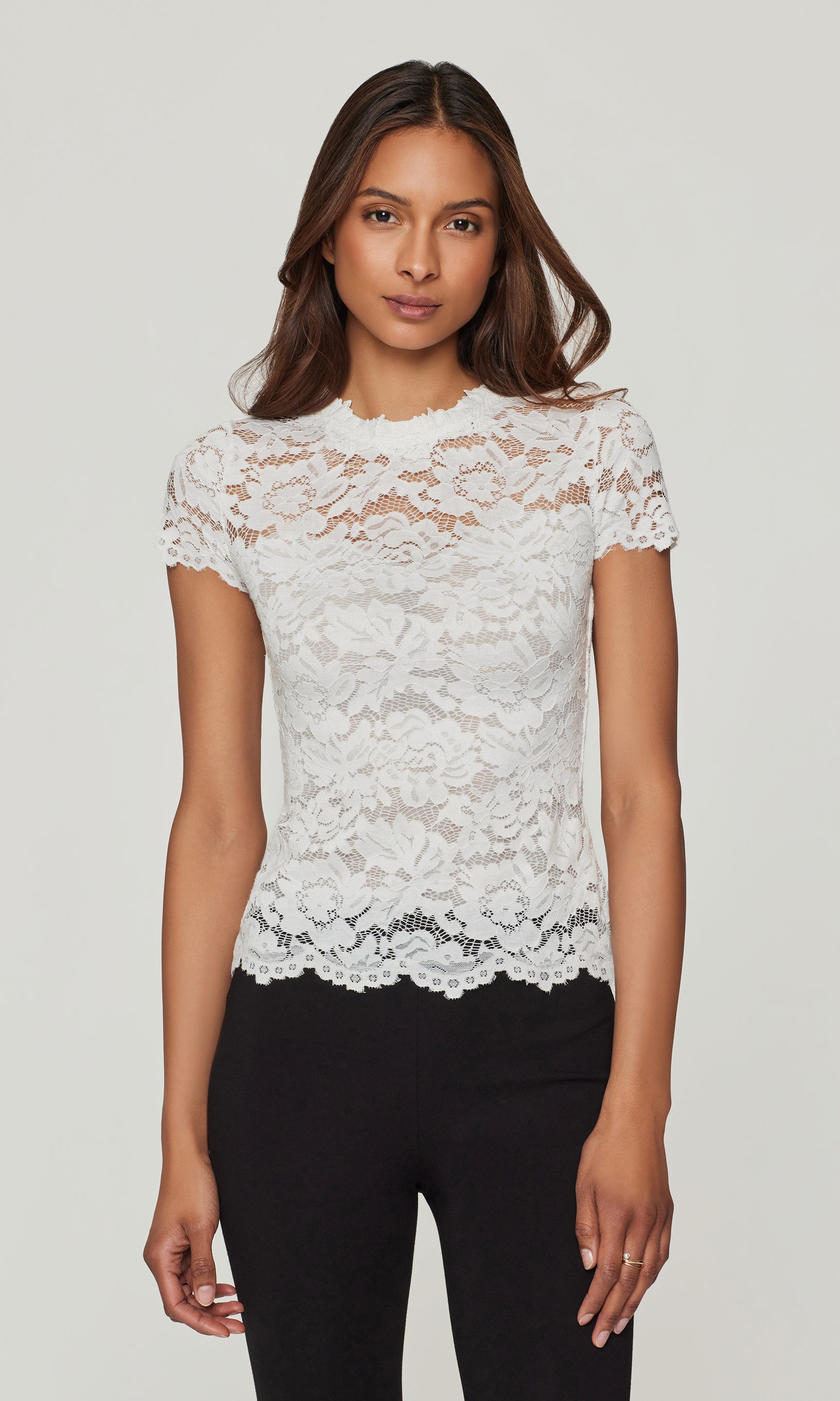 Woman wearing a white lace top against a plain background