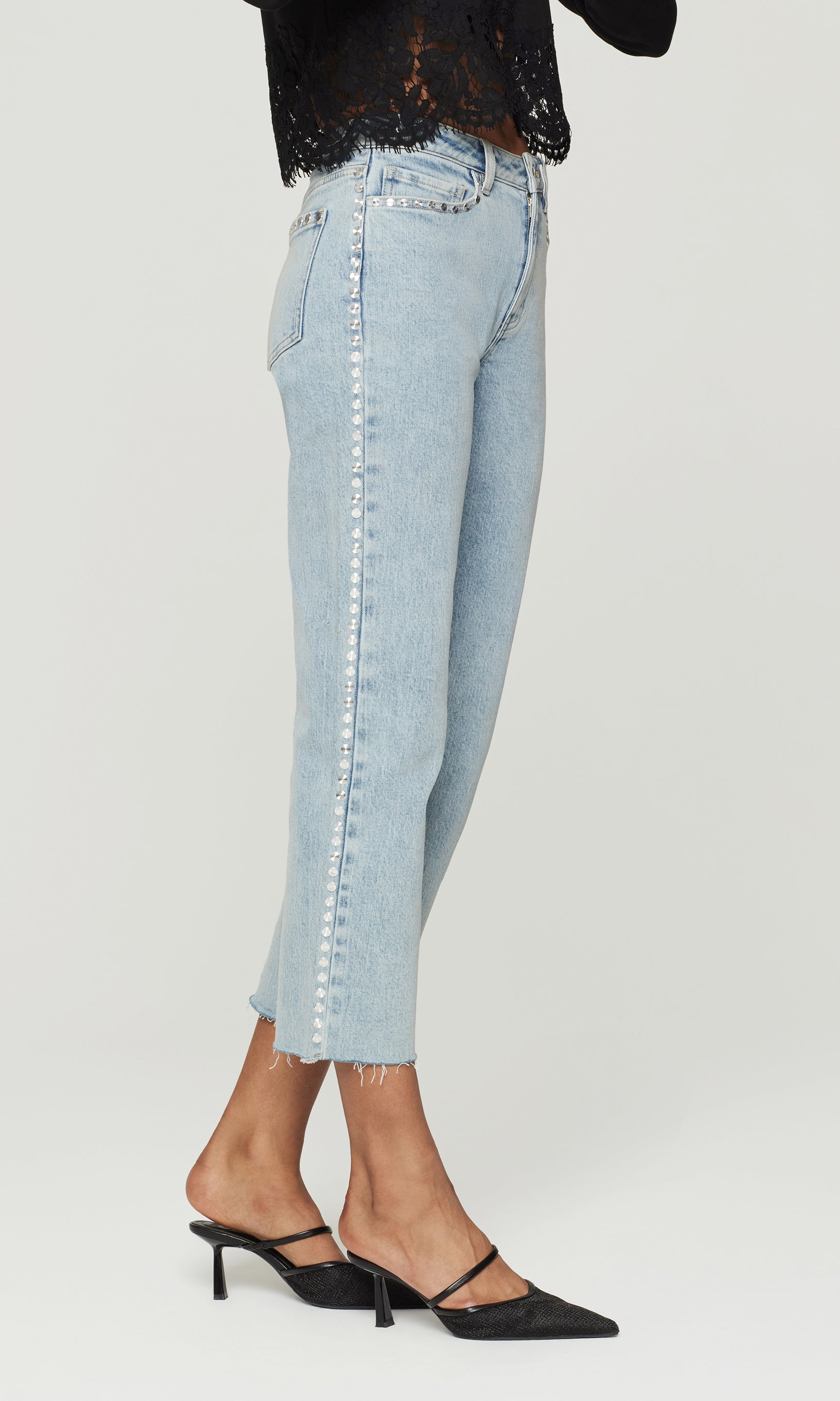 Light blue jeans with silver studs down the side worn by a person on a white background