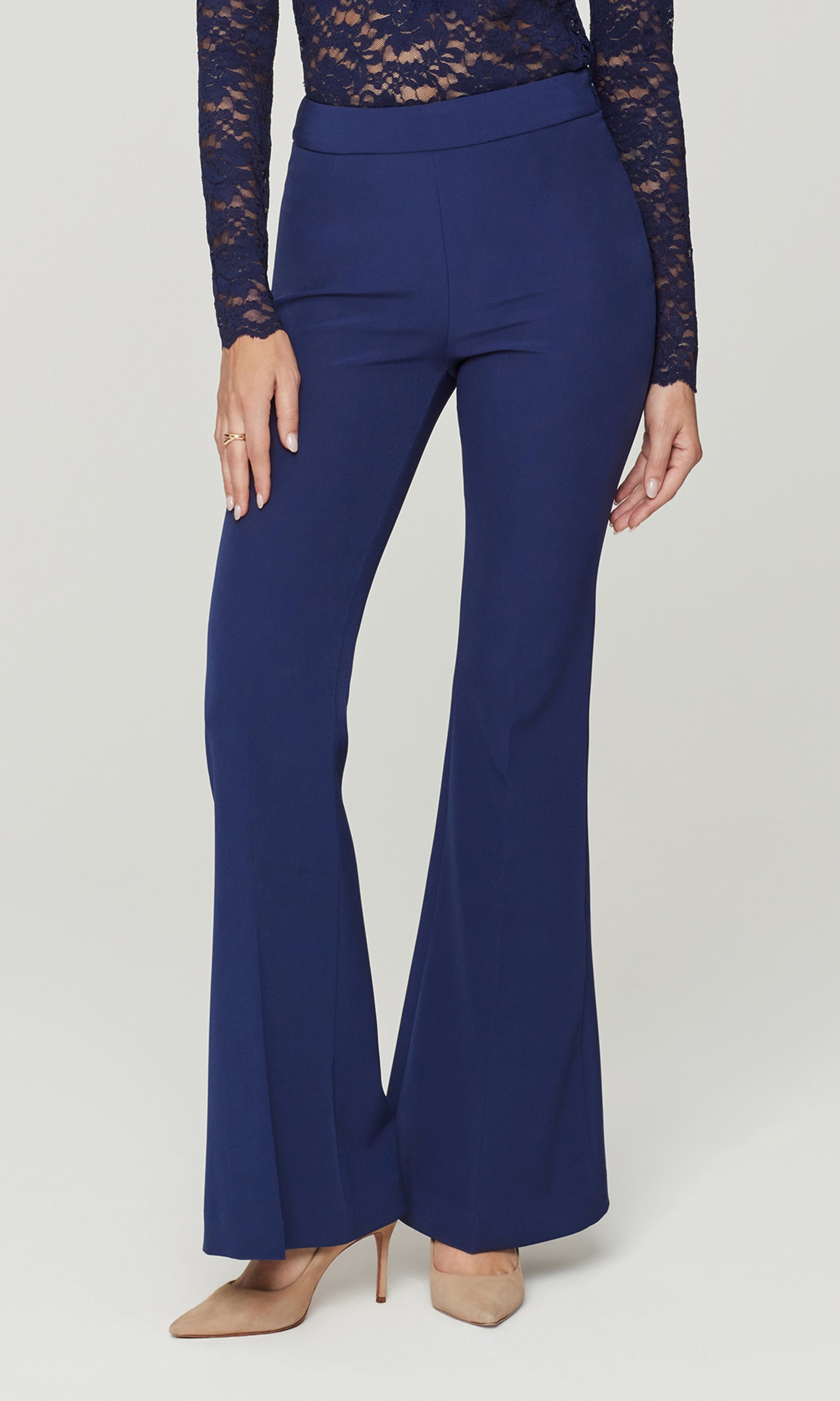 Blue flared pants worn with a lace top on a white background
