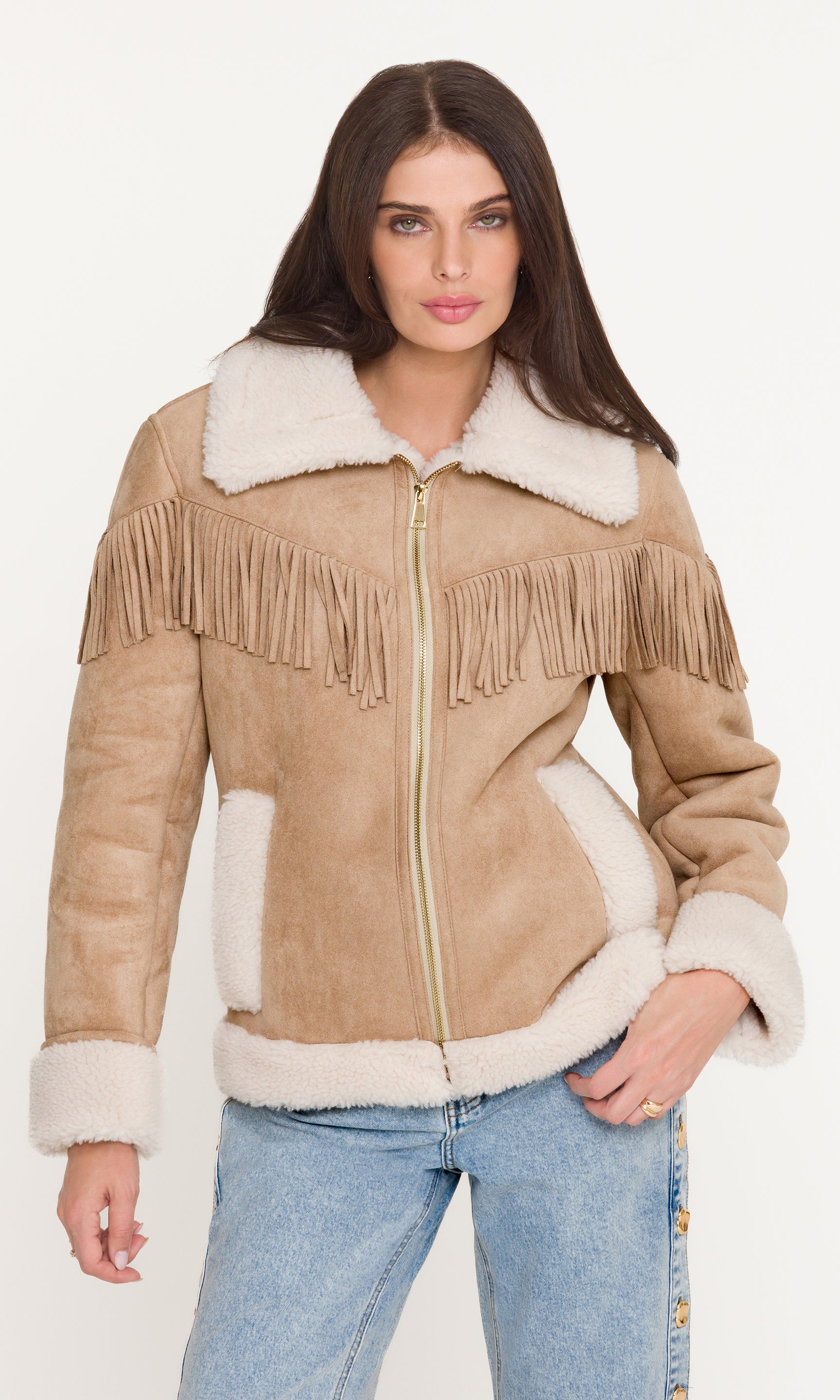 Woman wearing a beige suede jacket with white fur lining and fringes on a white background