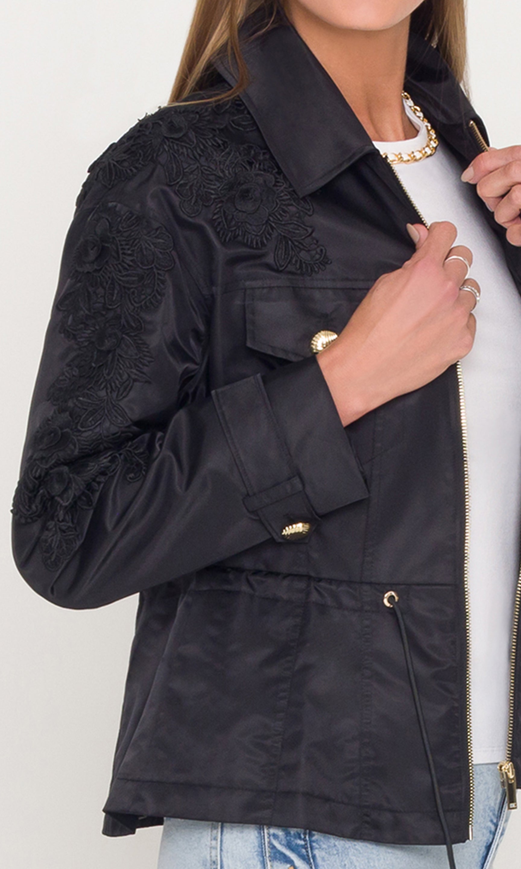 Close-up of black jacket with floral embroidery on a white background