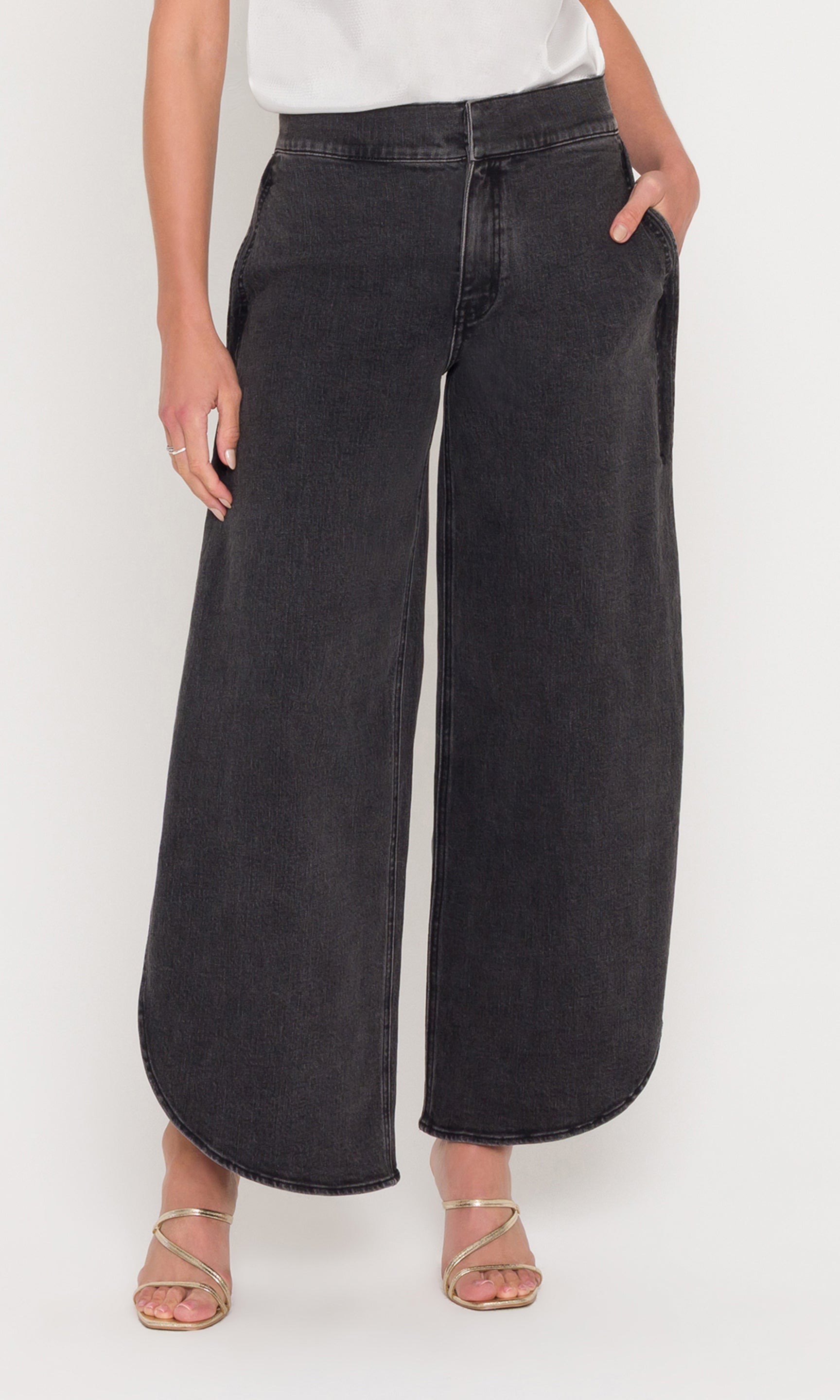 Person wearing black wide-leg jeans on a white background