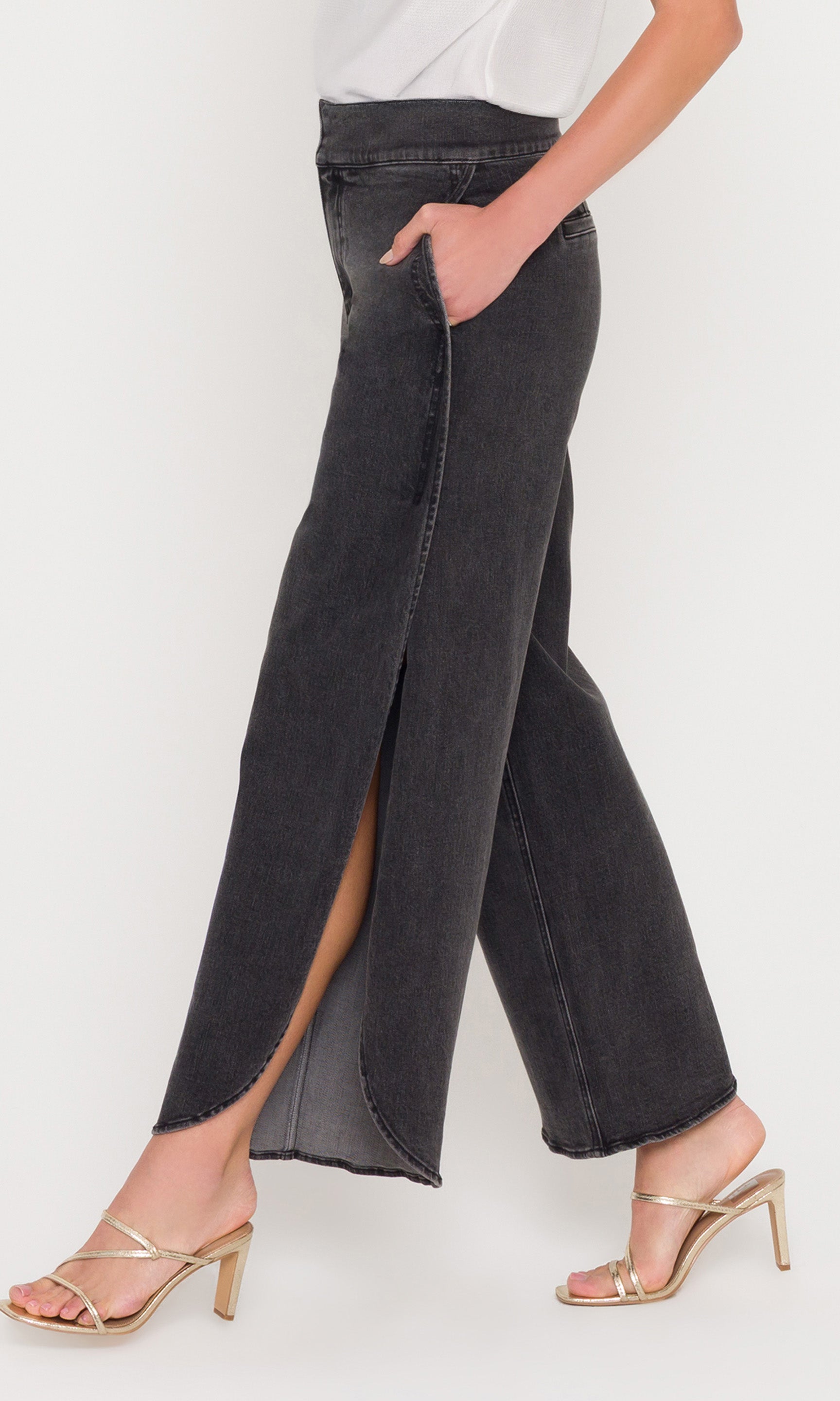 Side view of black wide-leg jeans with a side split worn by a person on a white background