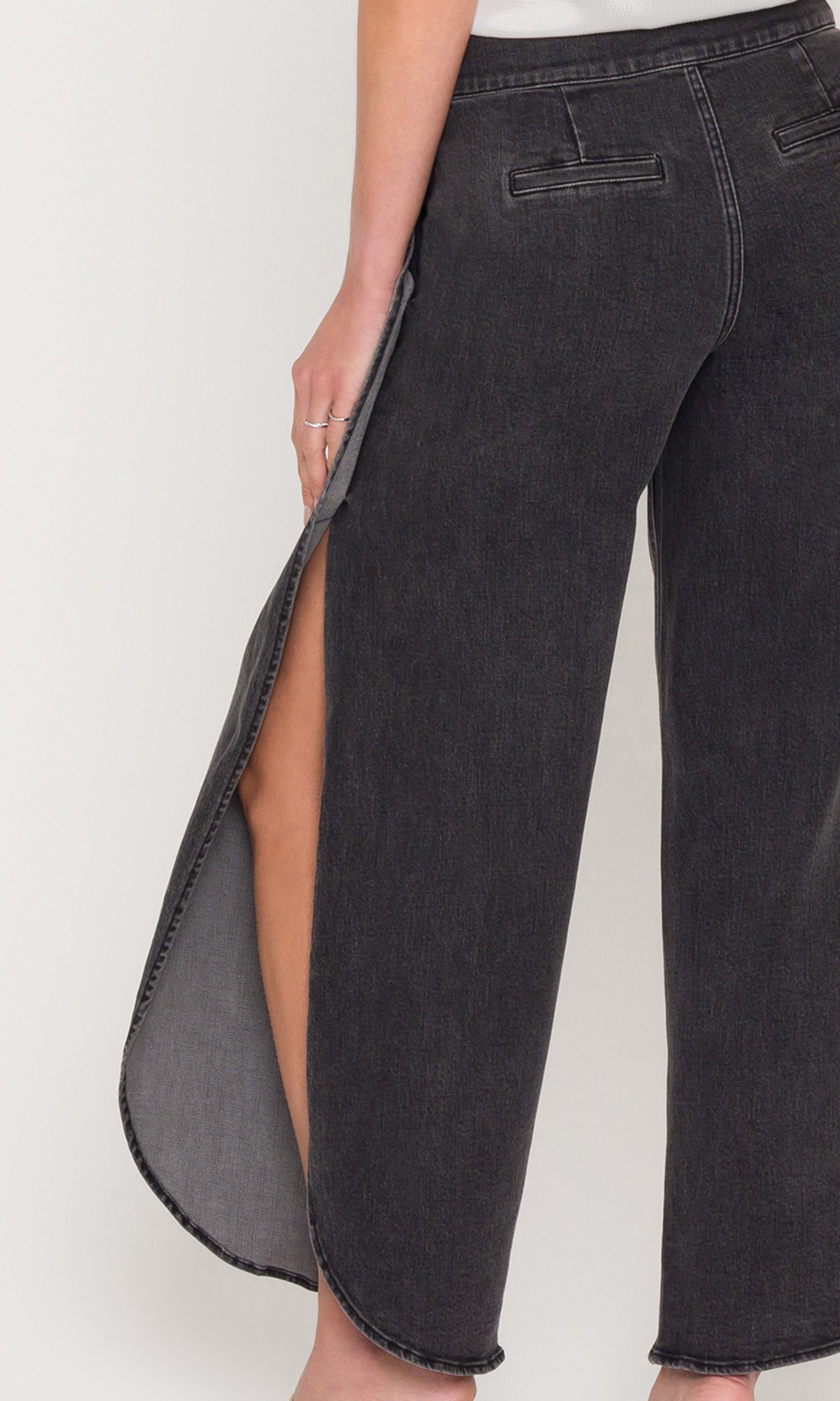 Close-up of black jeans with a high slit on a white background