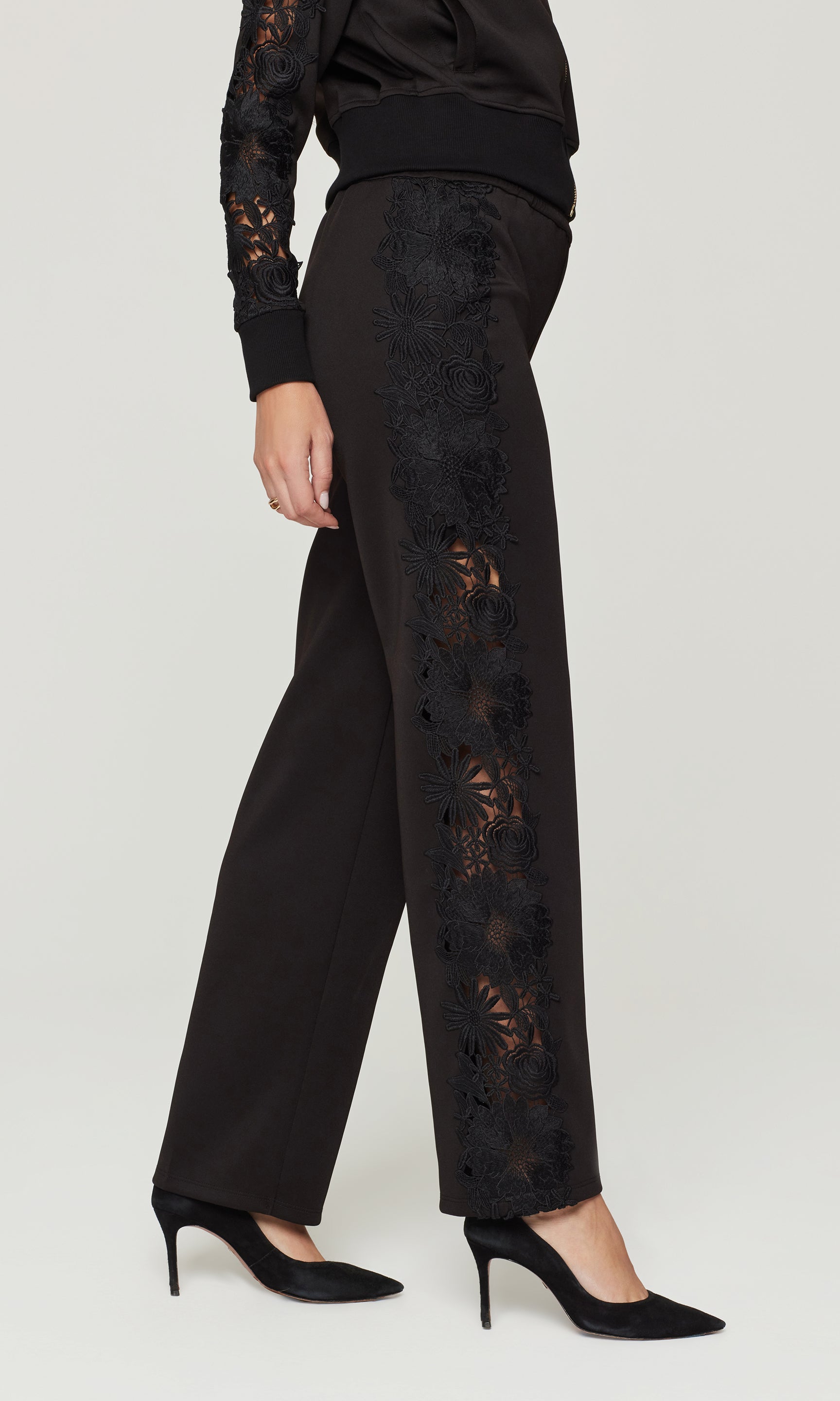 Black lace pants worn by a person on a white background