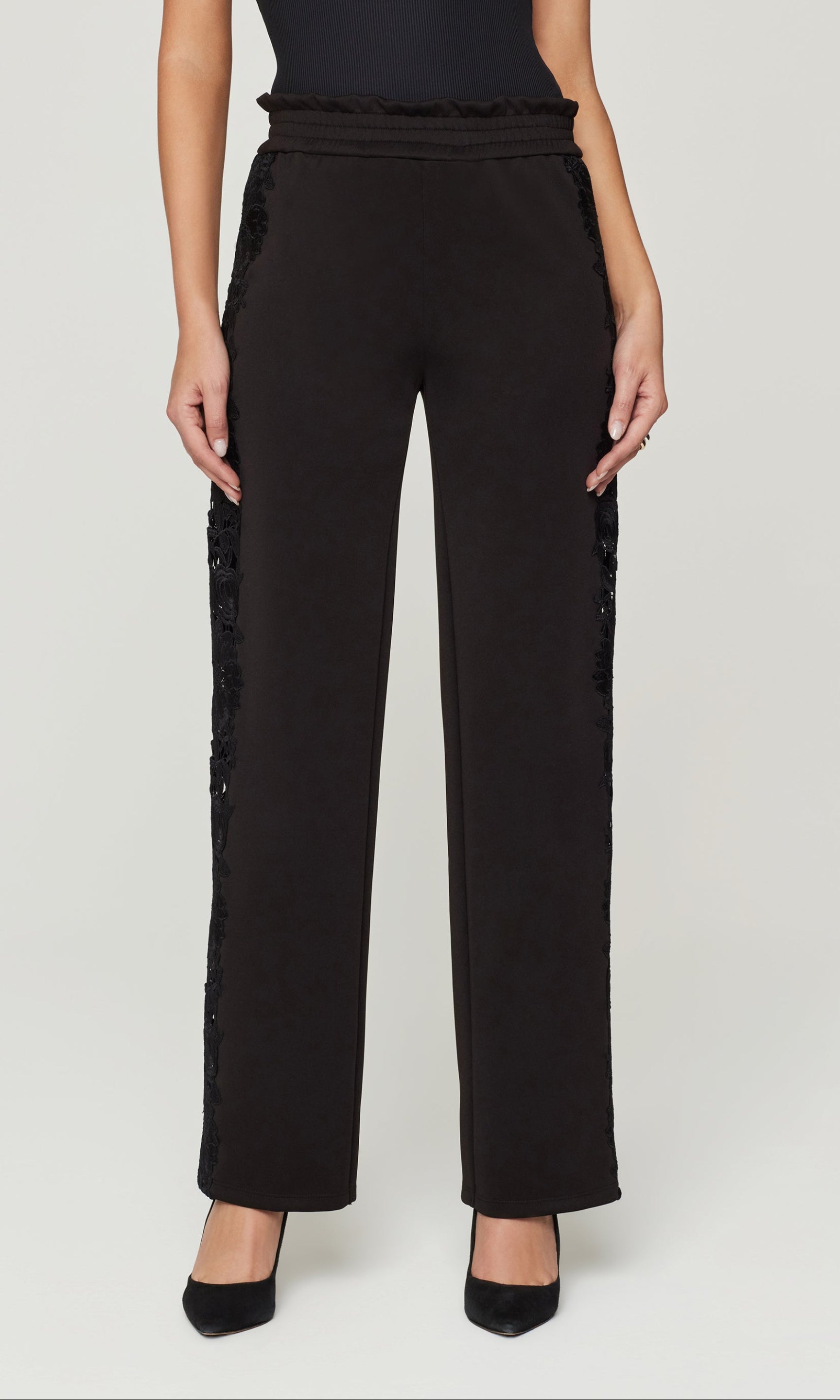 Black pants with lace detailing on a white background