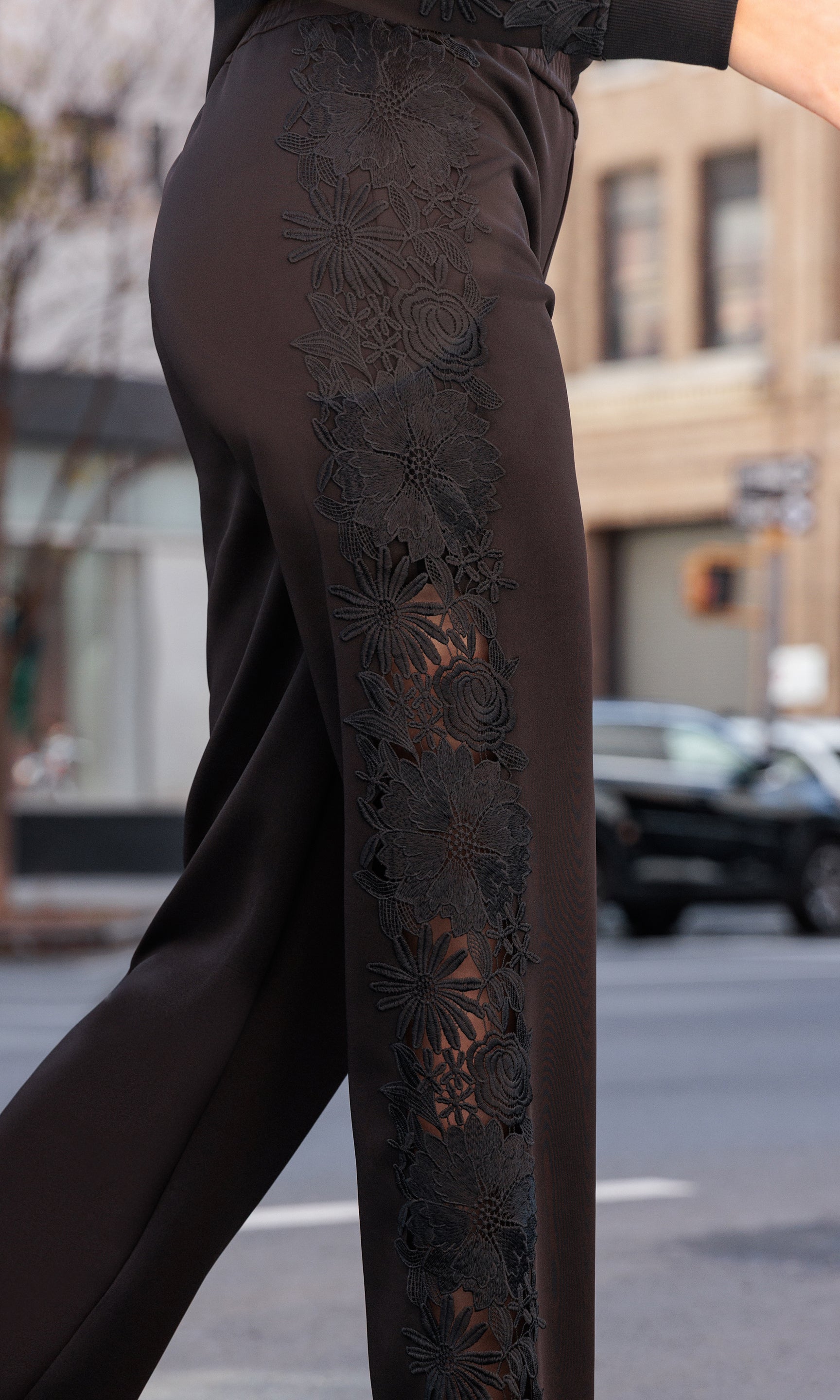 Black lace pants being worn on a blurred street background