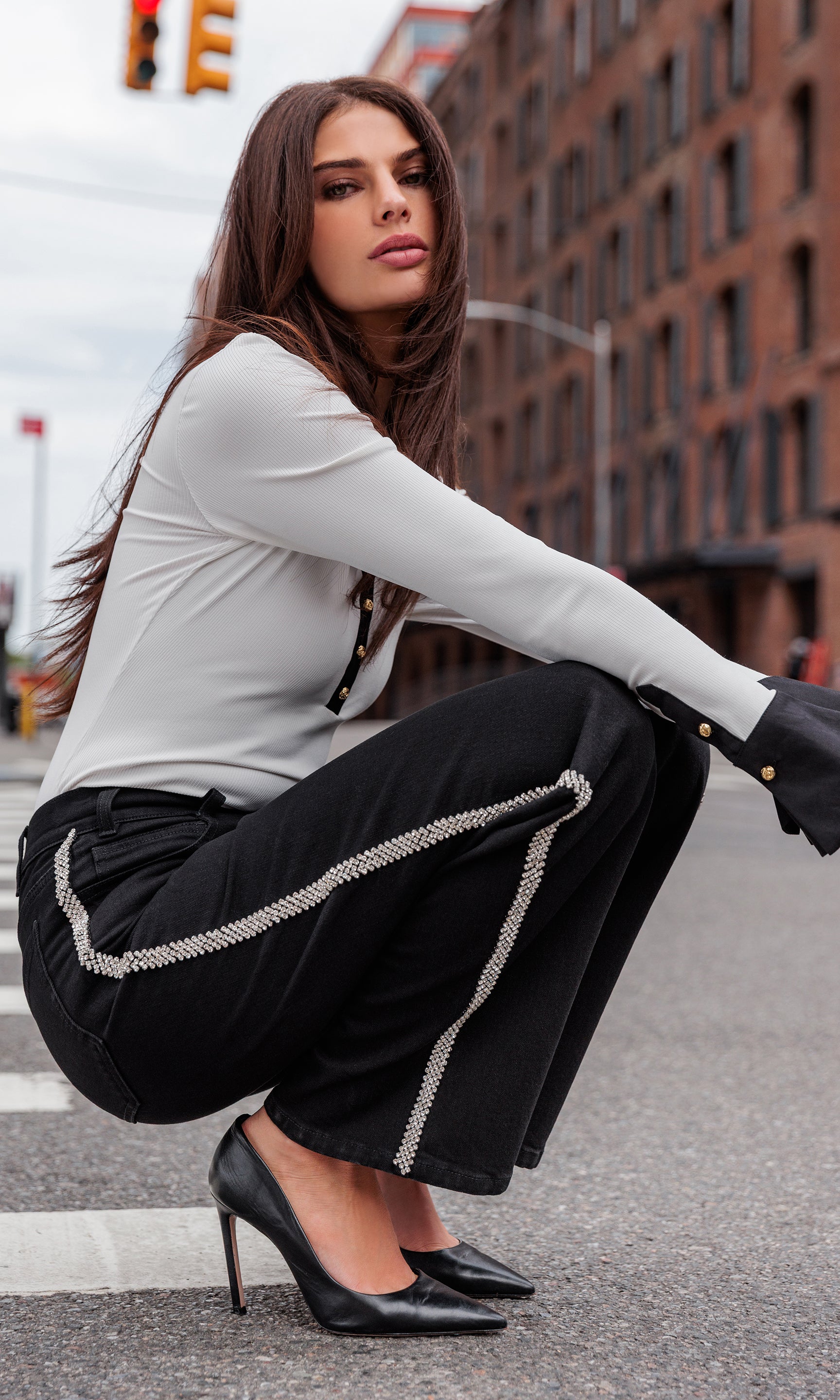 Woman in a stylish outfit with black pants and high heels on an urban street.