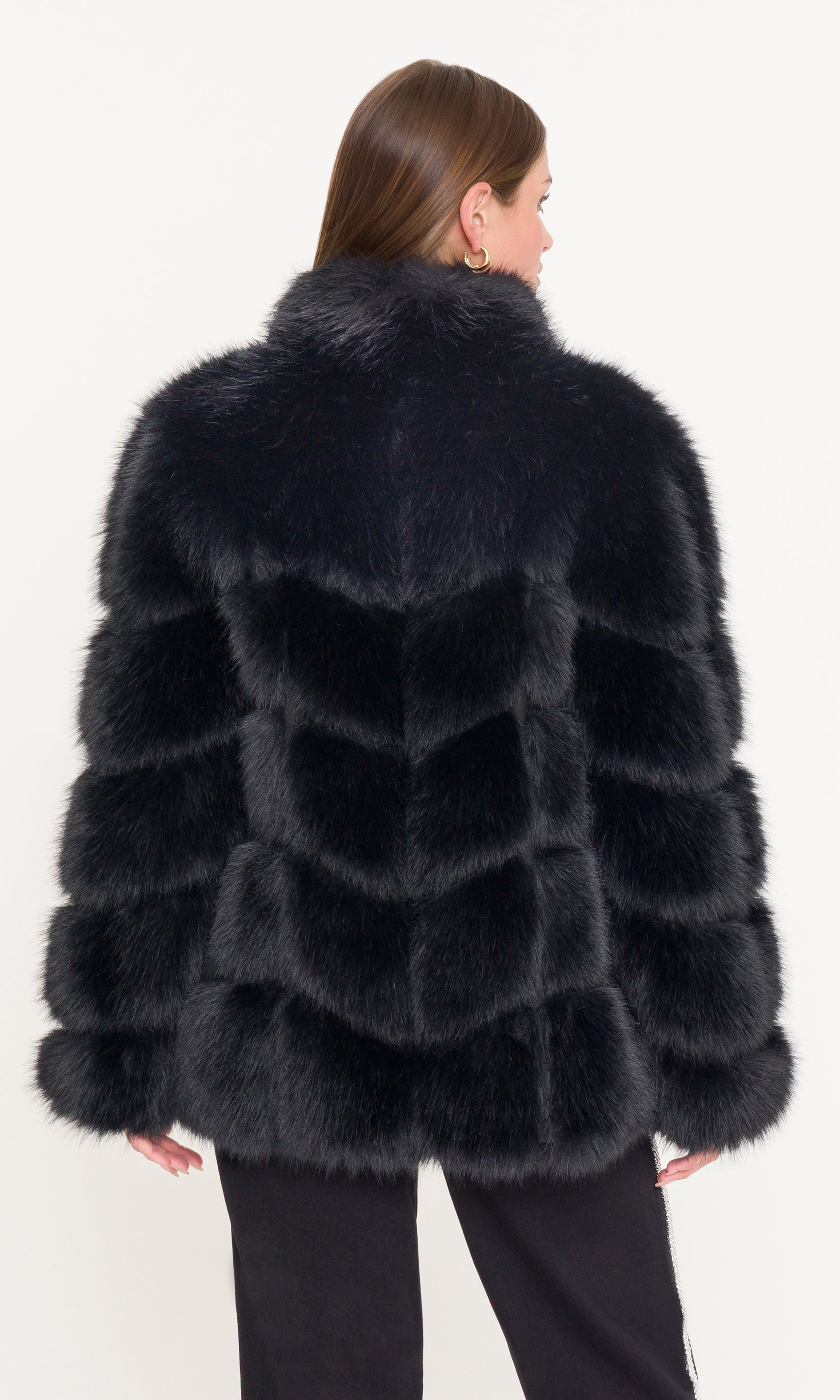 Back view of black fur coat worn by a person on a white background