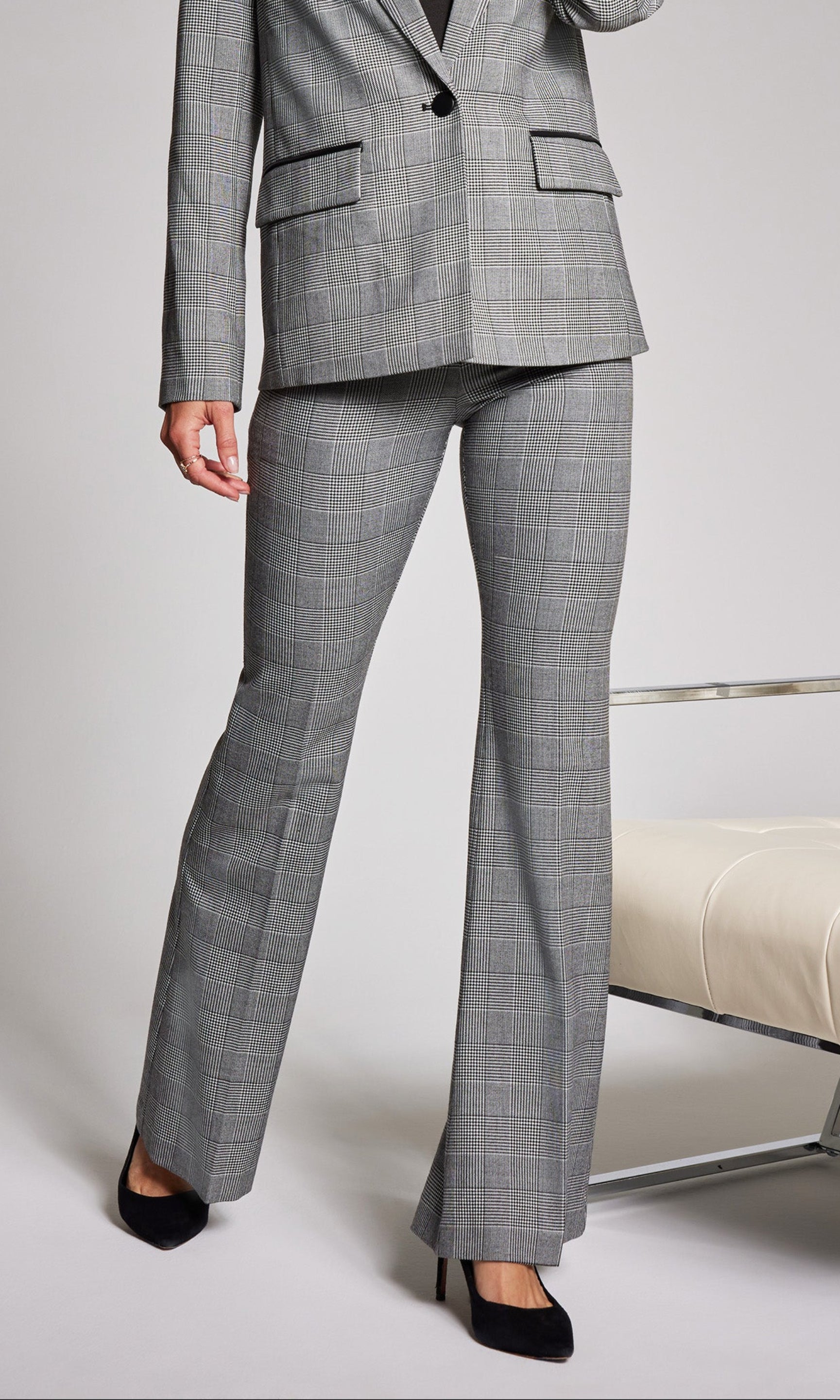 Woman wearing a gray checkered suit standing against a plain background
