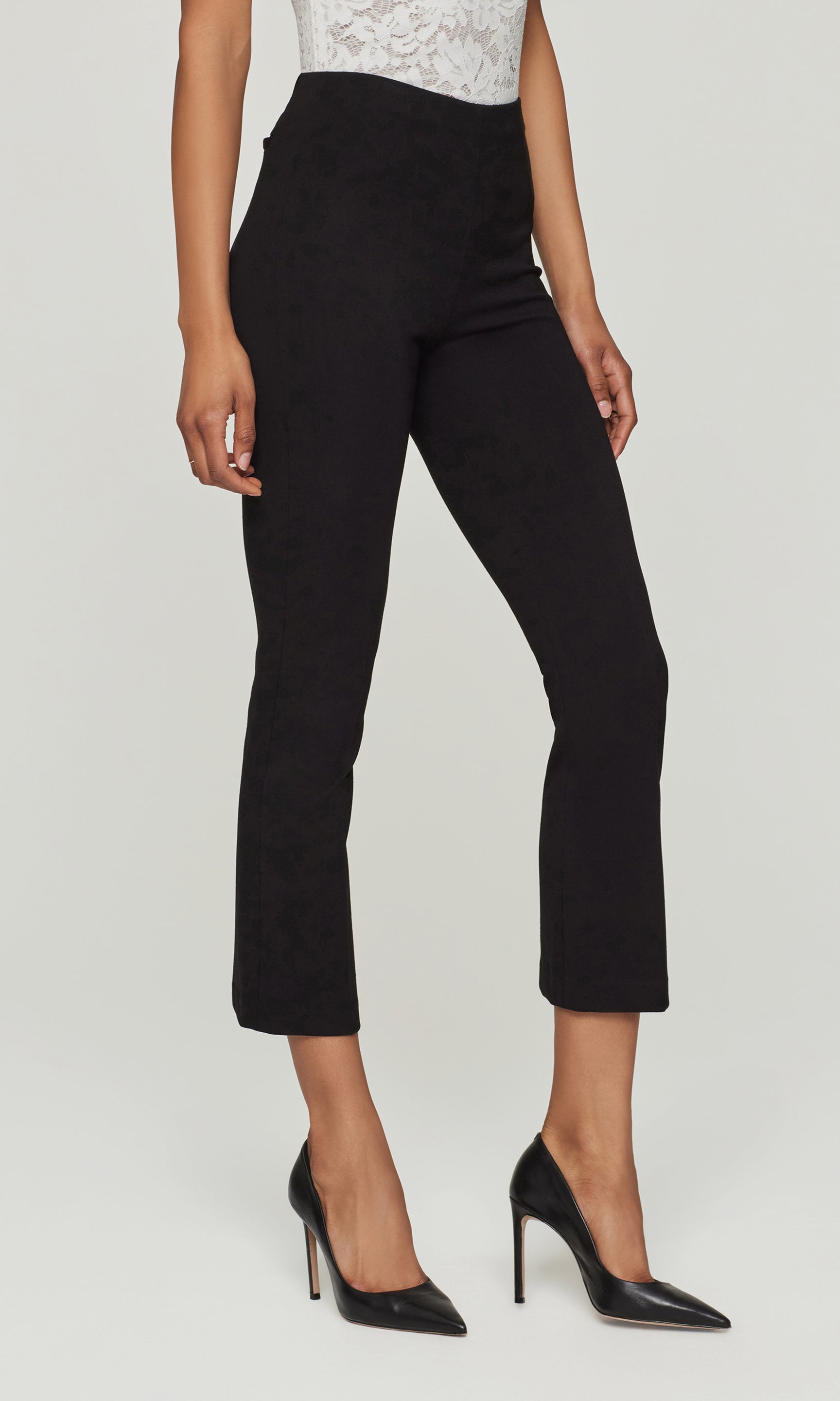 Side view of person wearing black pants and black high heels on a white background