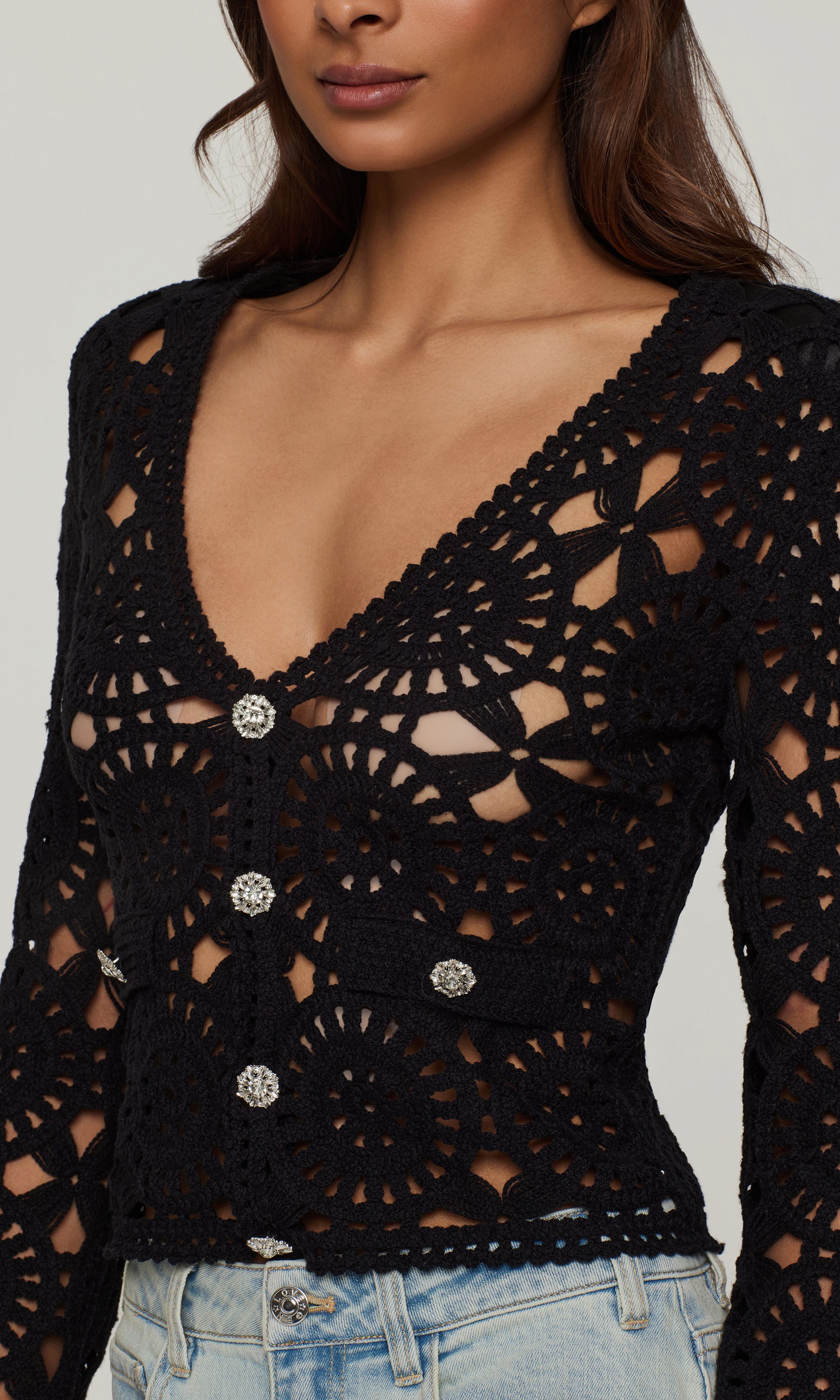 Black crochet top with crystal button details worn by a model against a neutral background