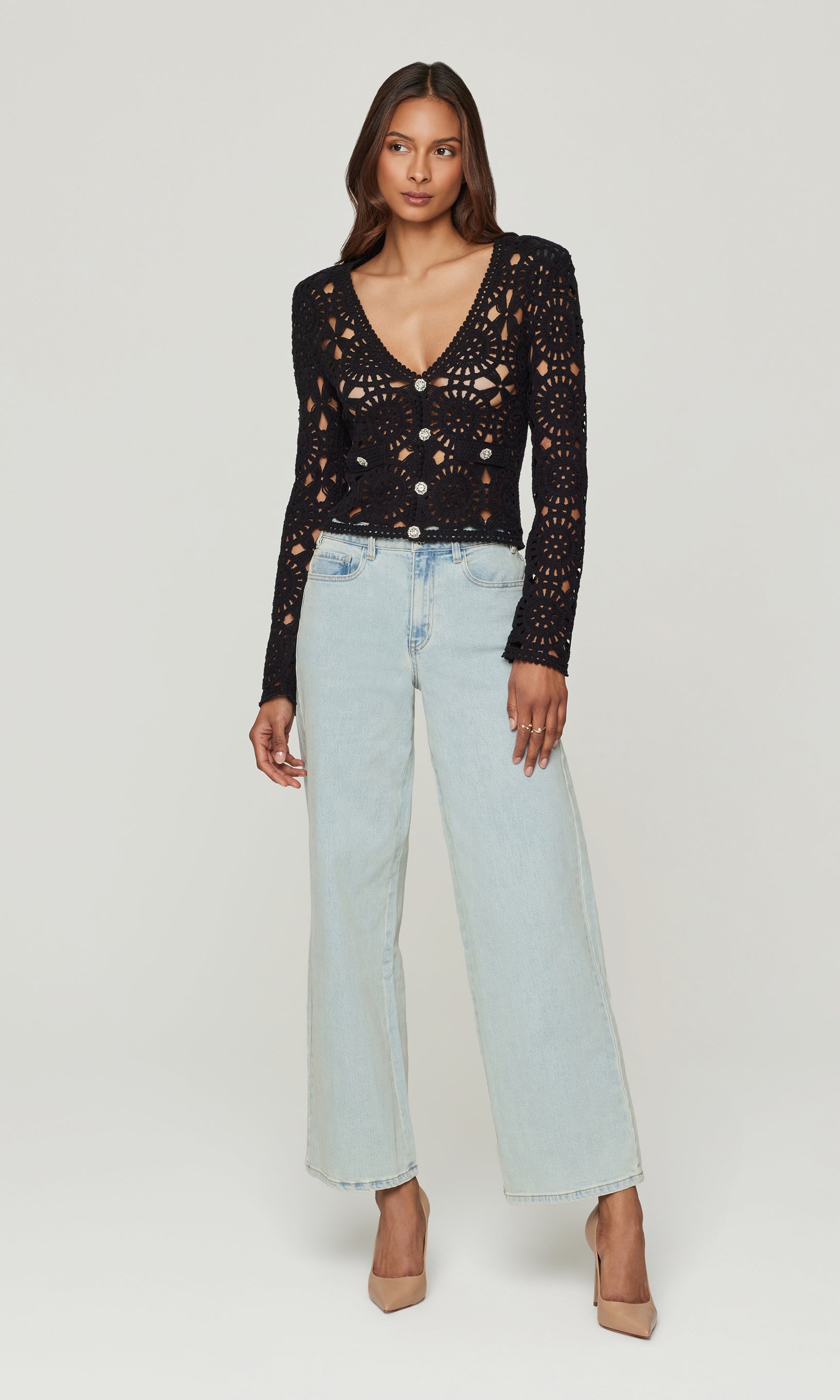 Woman wearing a black lace top and light blue jeans on a white background