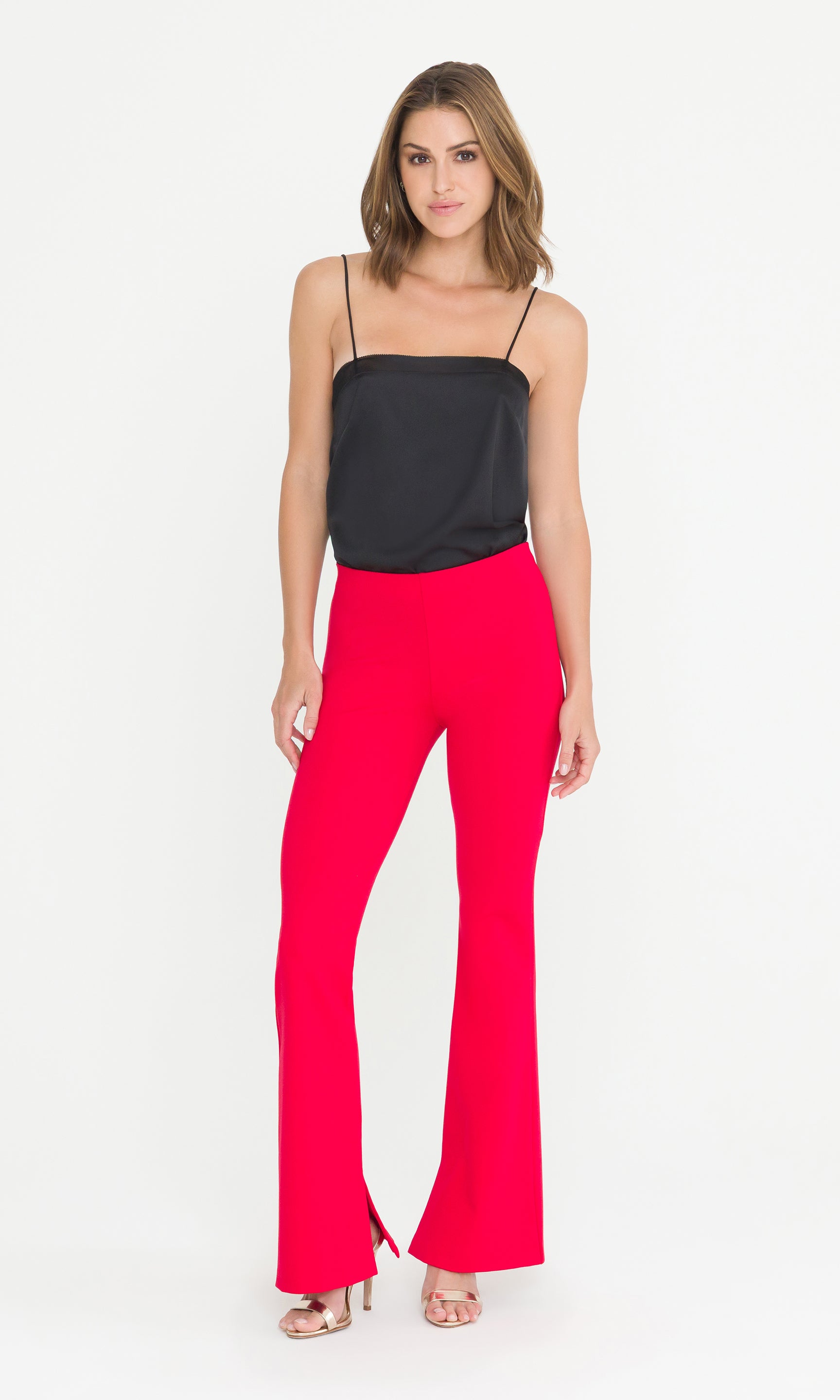 Full body image of model wearing a black top and red pants on a white background