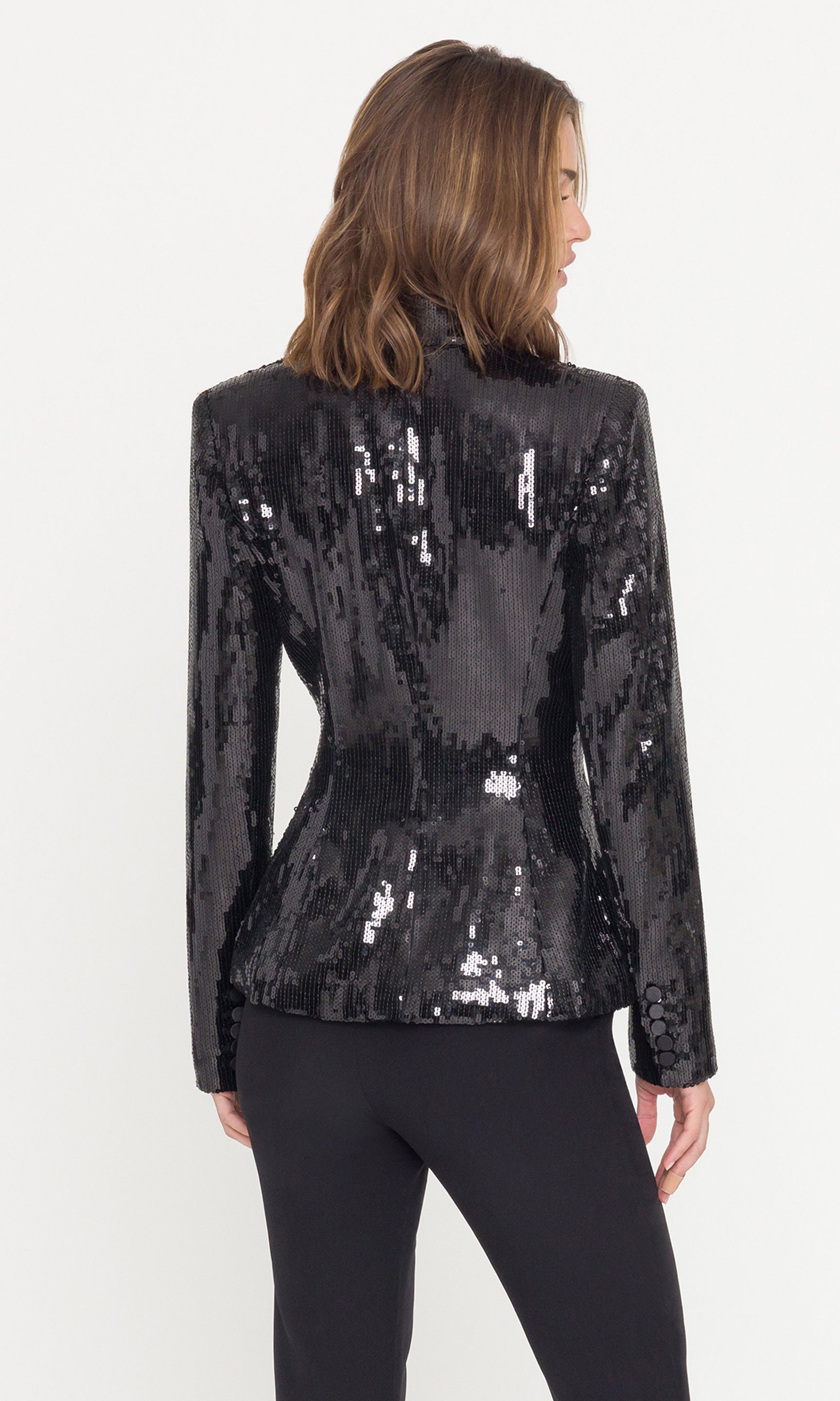 Back view of black sequin jacket worn by a model on a white background