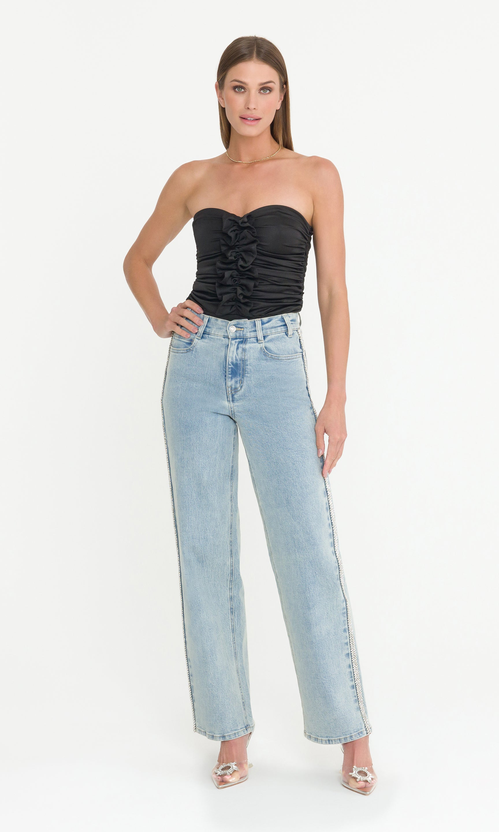 Full body image of woman wearing a black strapless top and light blue jeans on a white background