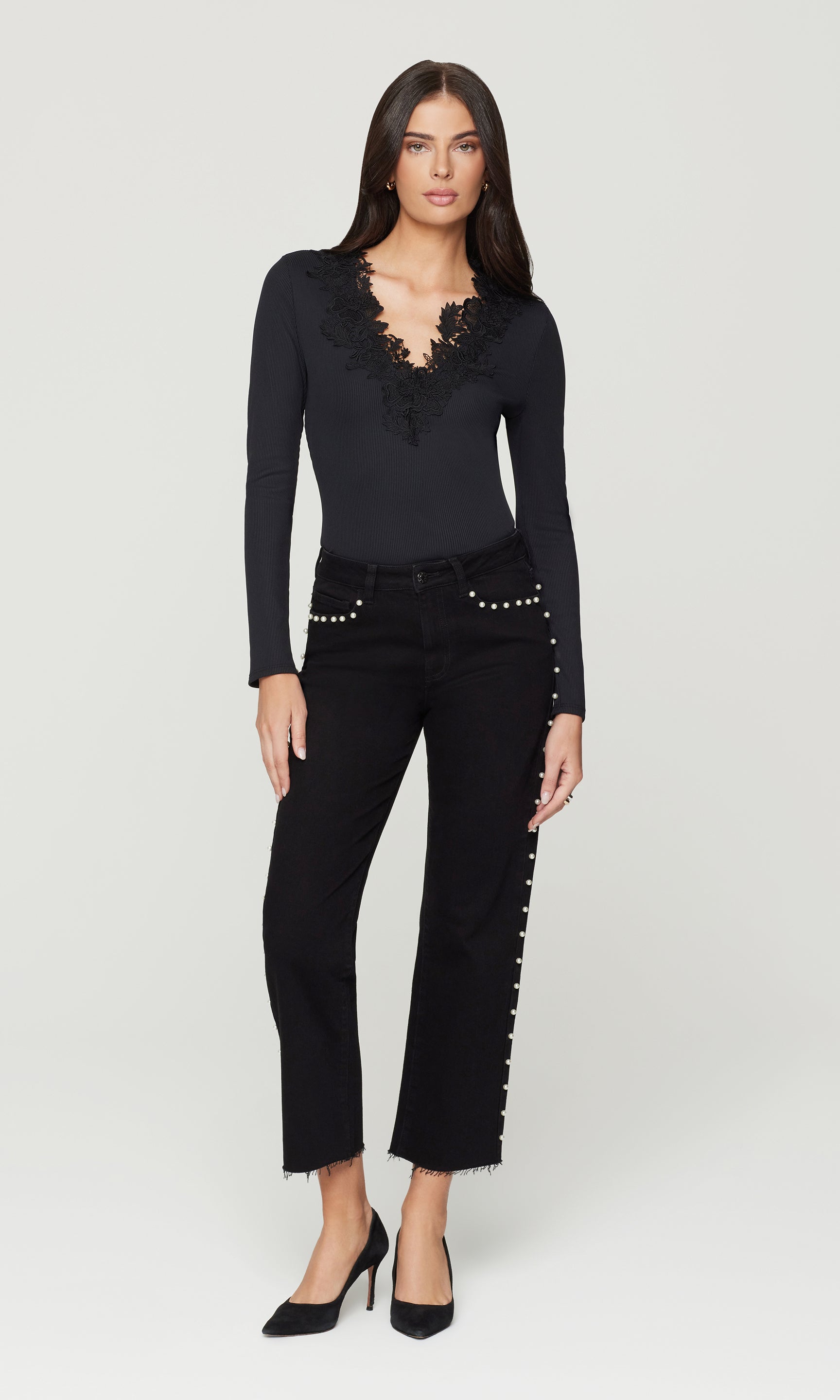 Woman wearing a black outfit with studded details on a white background