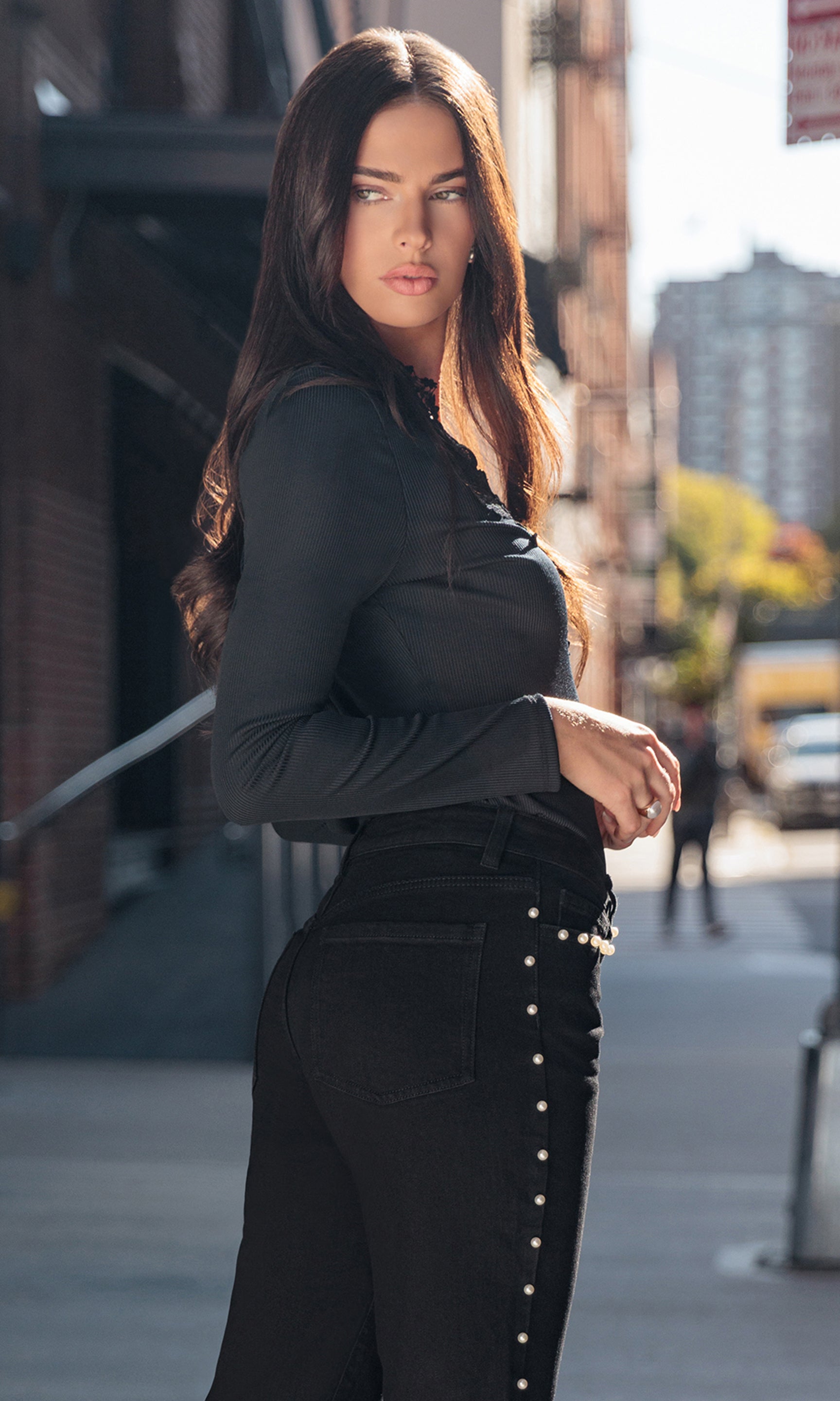 Woman in a black outfit standing on a city street