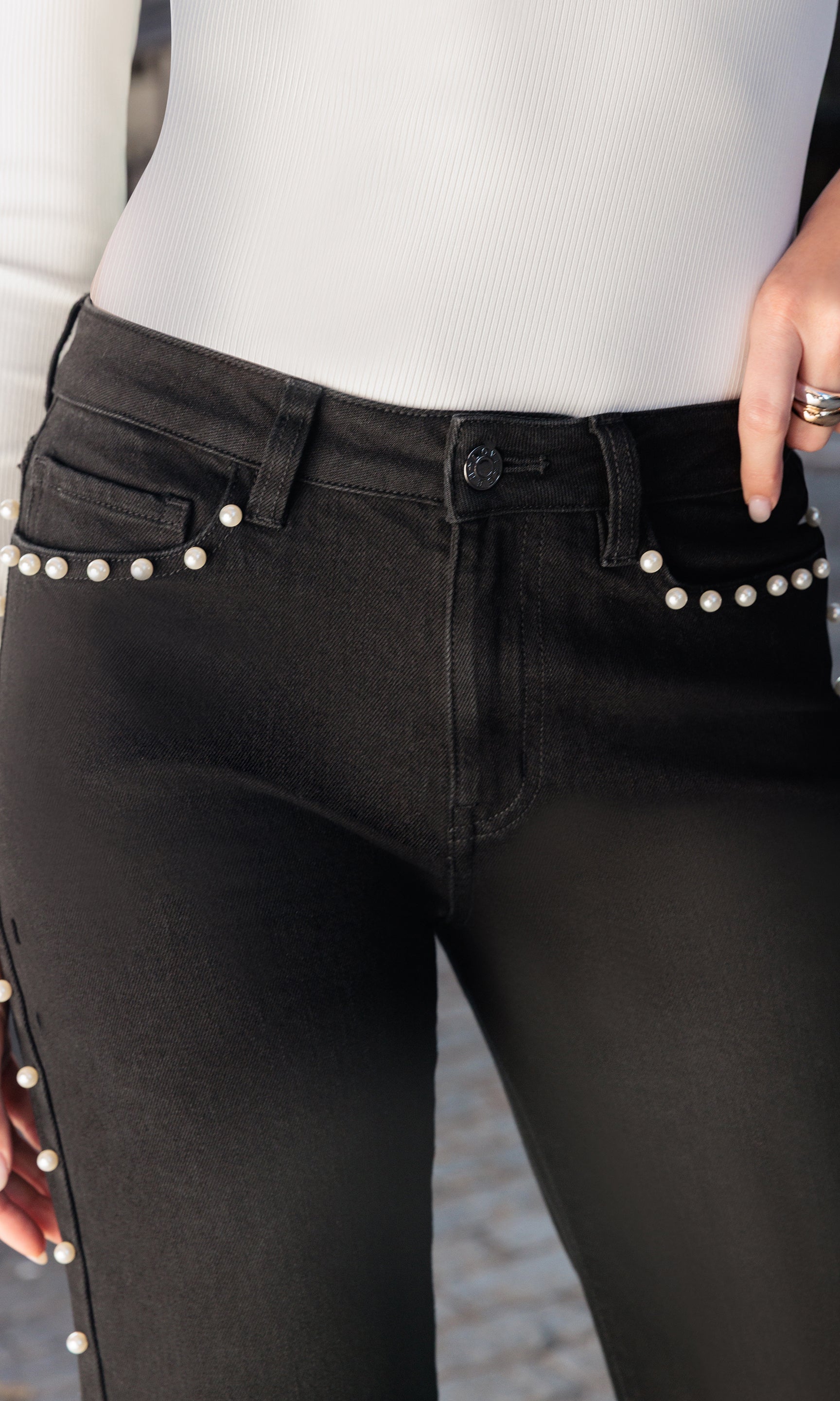 Black jeans with pearl embellishments worn by a person.