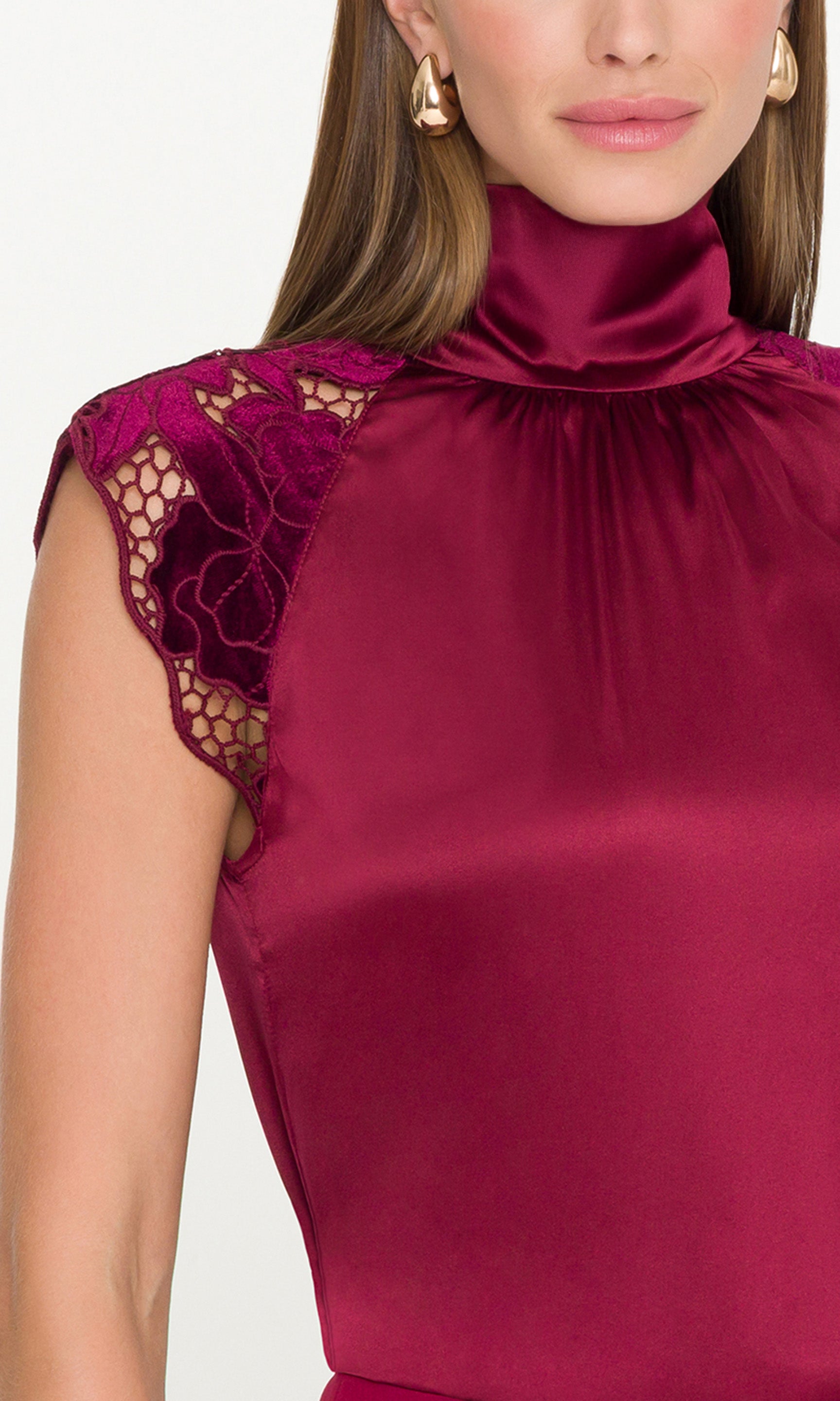 Close-up of a person wearing a burgundy top with lace sleeves on a white background