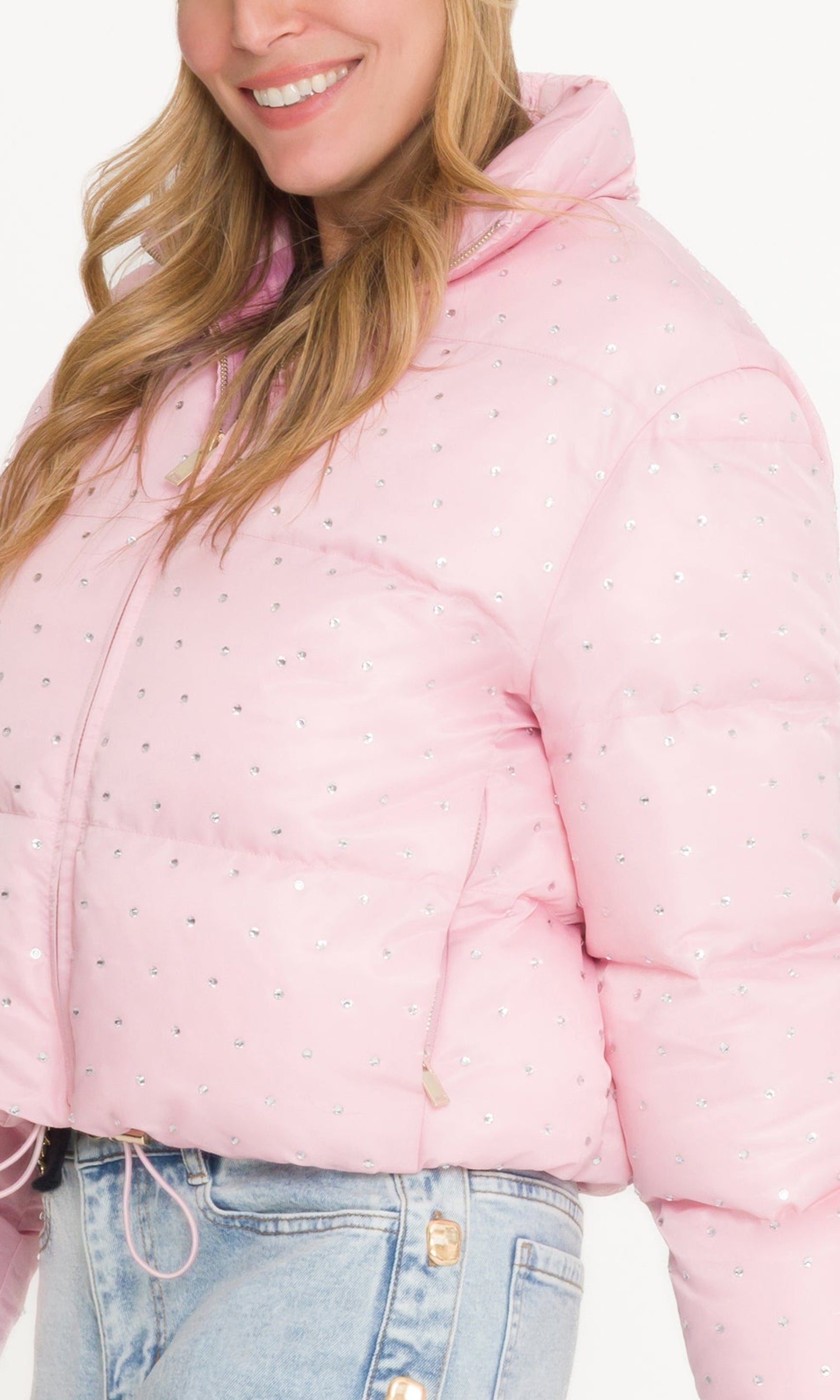 Pink polka dot puffer jacket worn by a person on a white background
