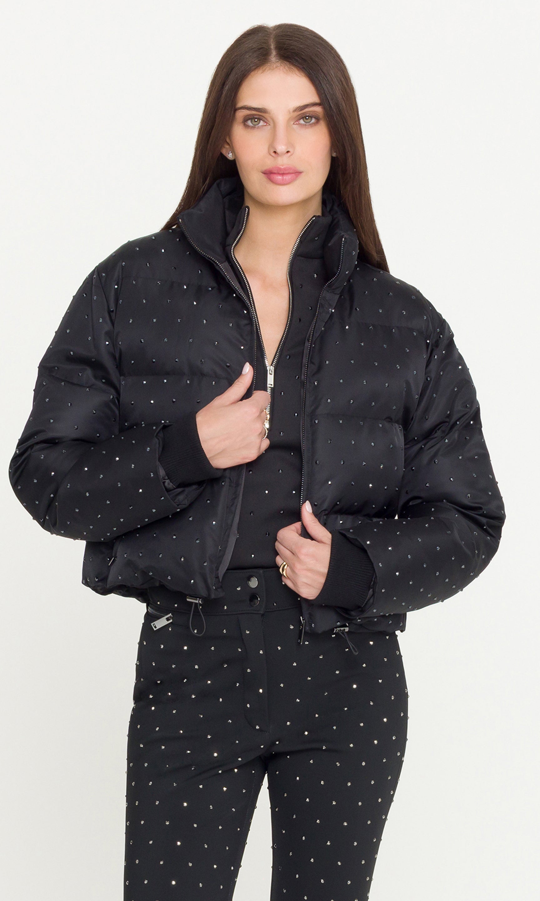 Model wearing a black crystal embellished puffer over a matching black jacket and pants