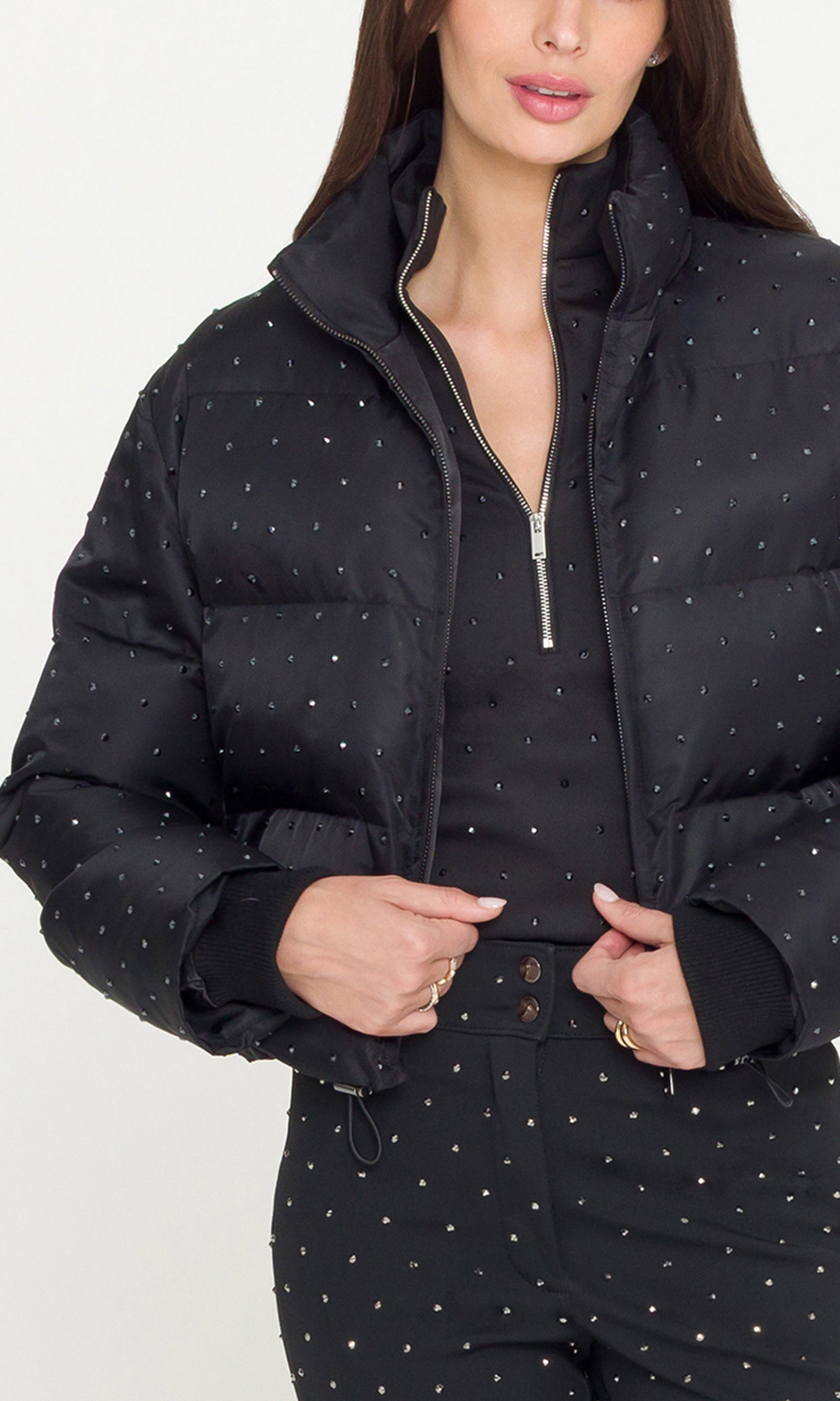 lose-up of Model wearing a black crystal embellished puffer over a matching black jacket and pants