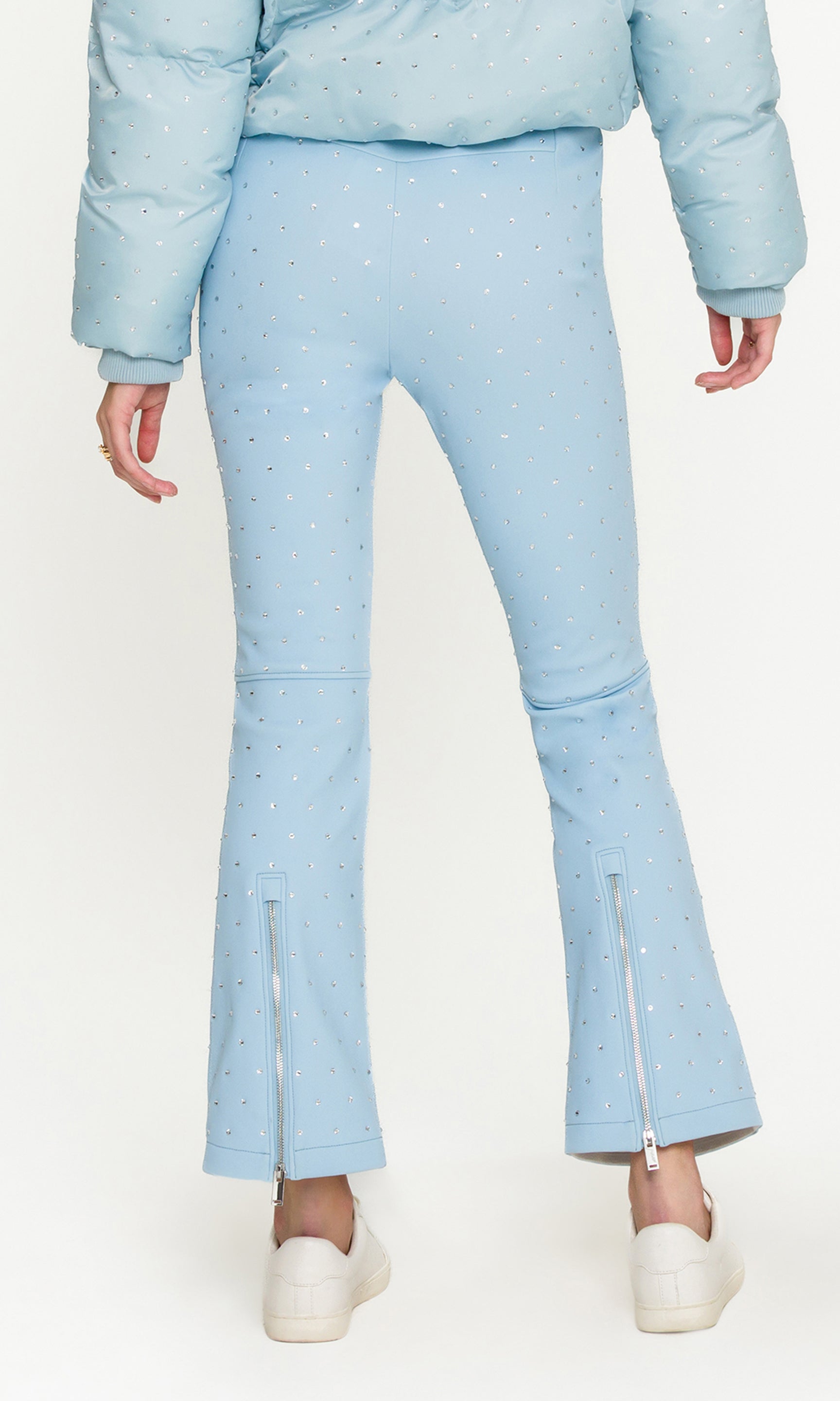 Back view of woman wearing light blue ski pants with white tennis shoes