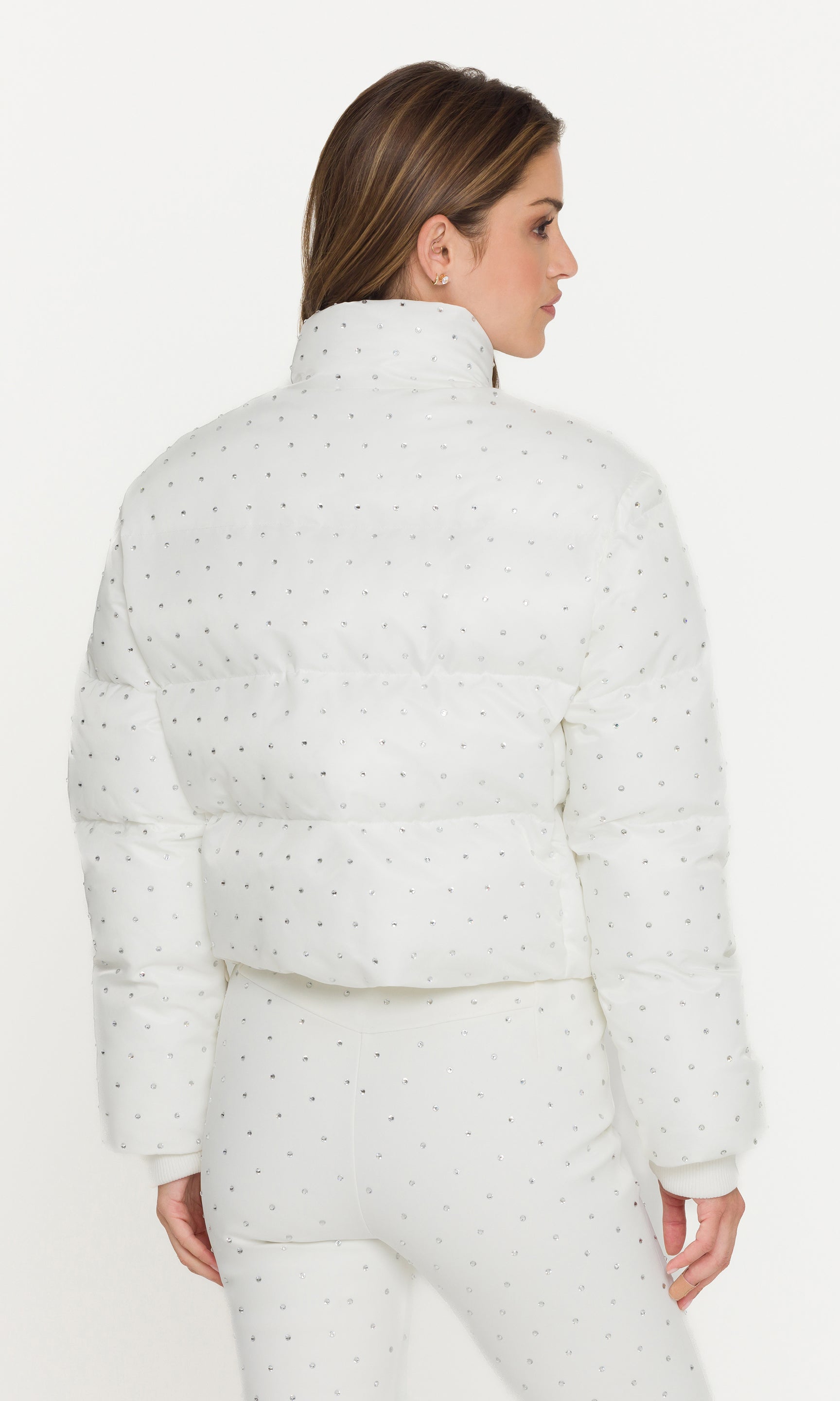 Woman wearing a white puffer jacket with a subtle pattern on a white background