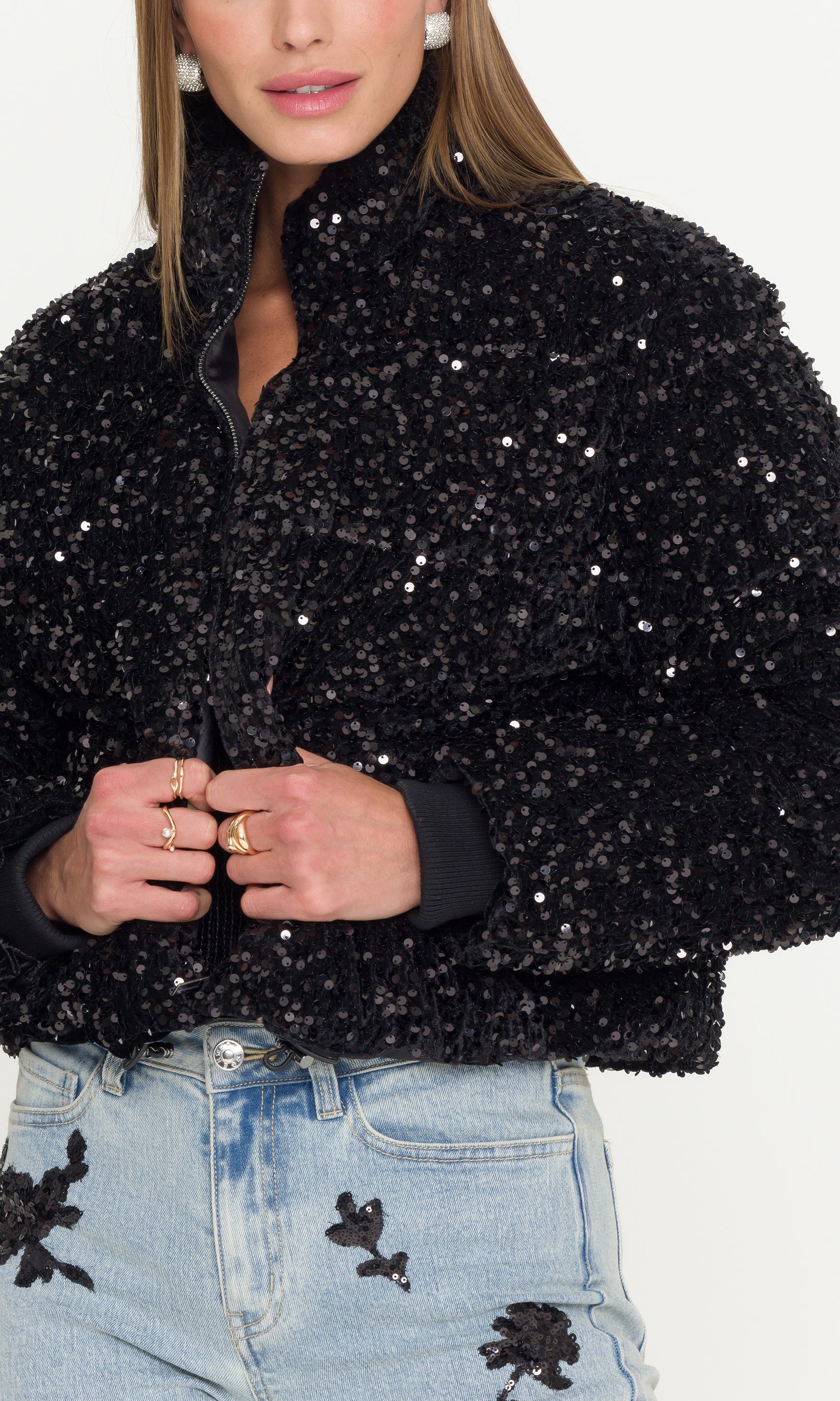 Close-up of black sequin jacket worn by a person on a white background
