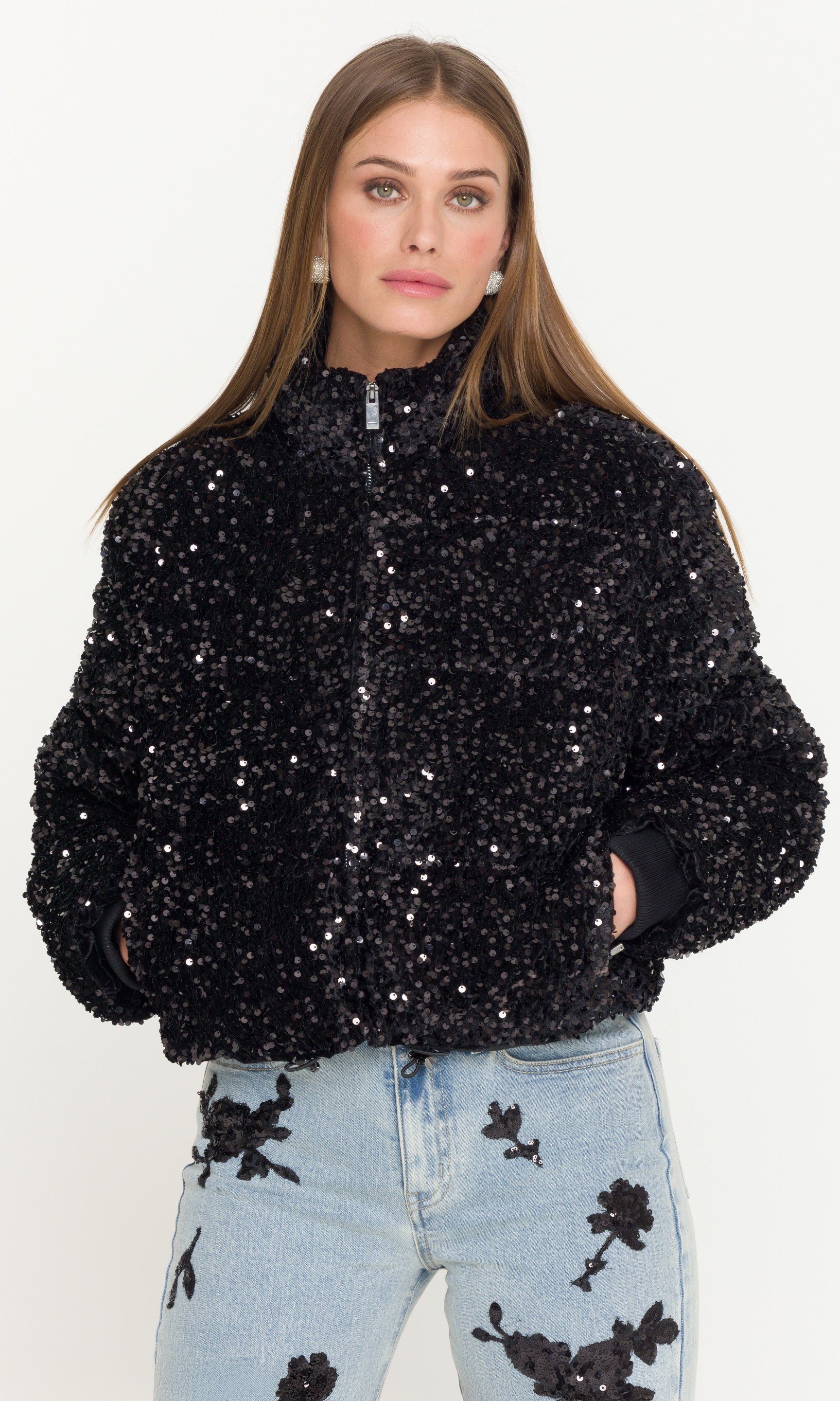Woman wearing a black sequin jacket zipped up on a white background