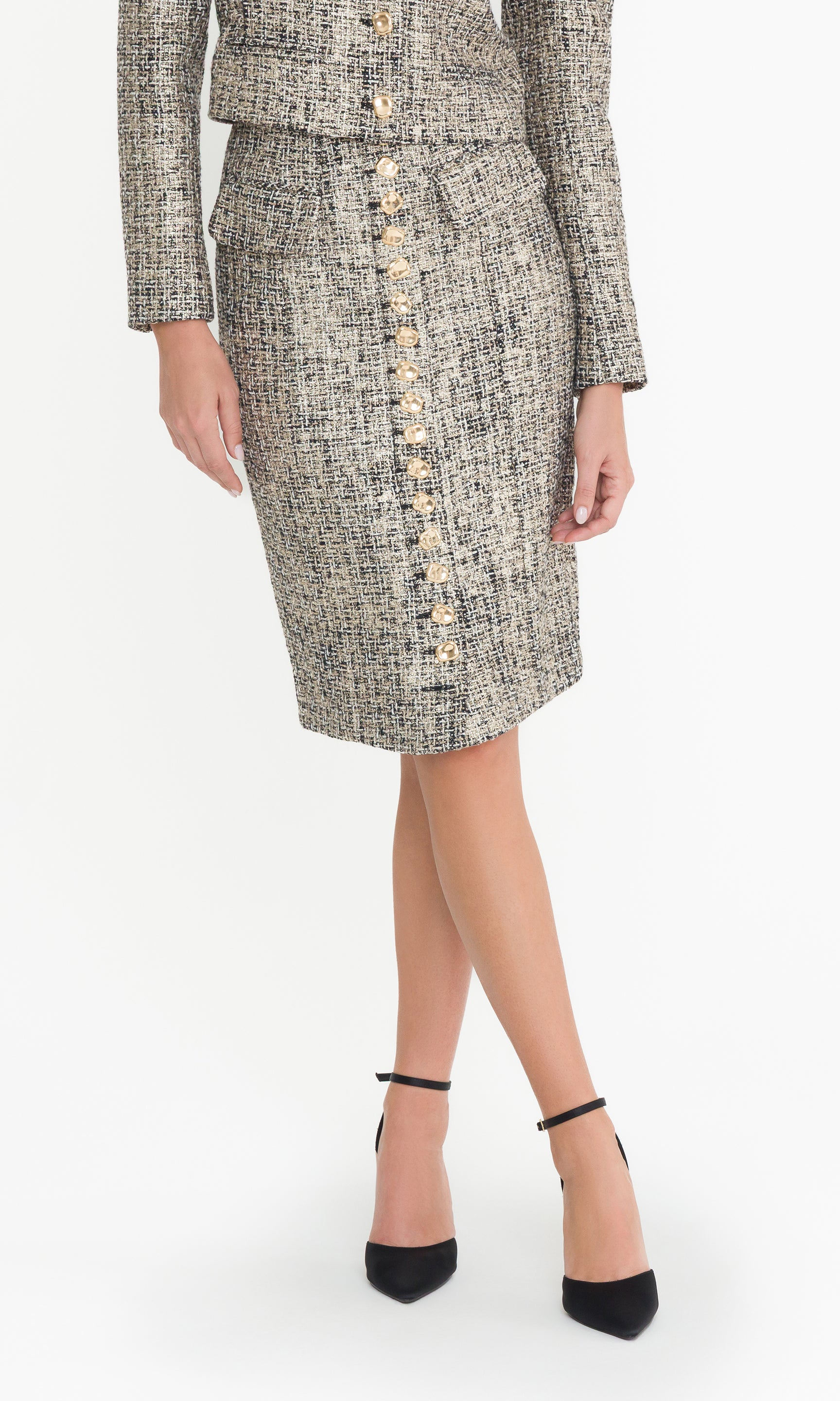 Front crop image of model wearing a gold multi tweed skirt suit with button details on a white background