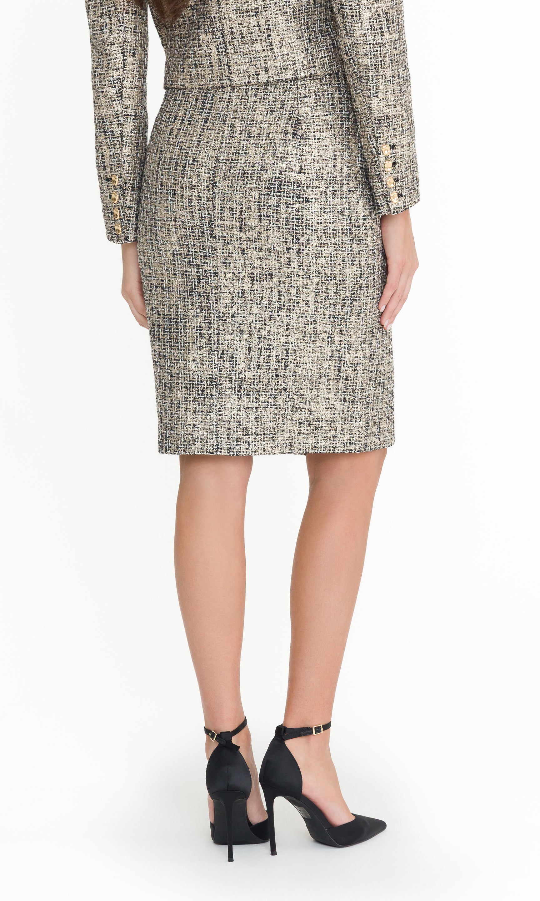 Back crop image of model wearing a gold multi tweed skirt suit with button details on a white background