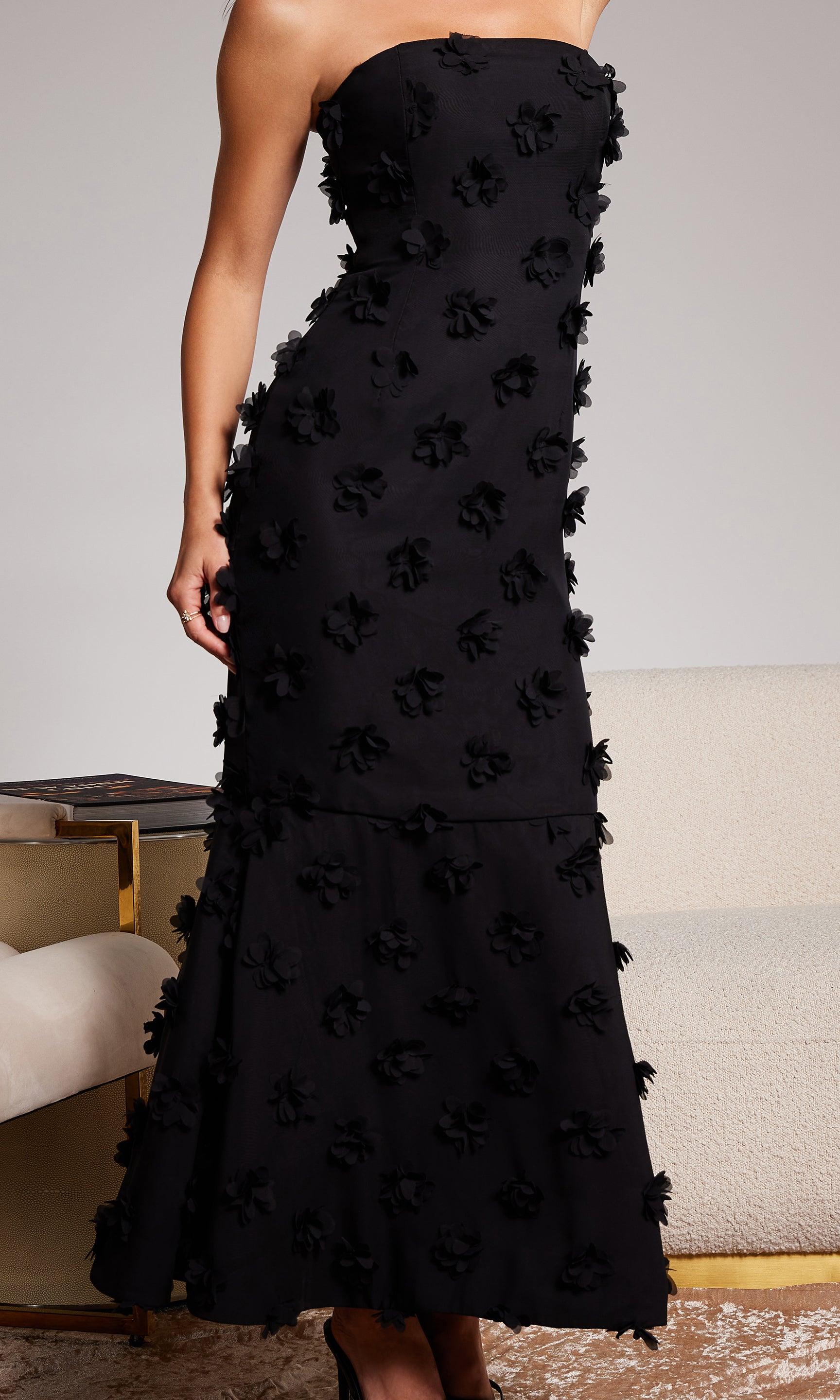 Black strapless dress with floral details on a neutral background