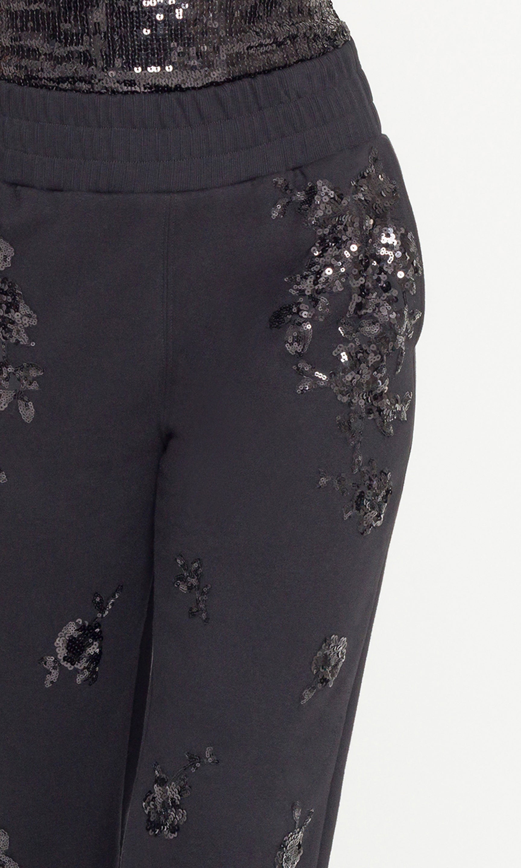 Black pants with sequin embellishments on a light gray background