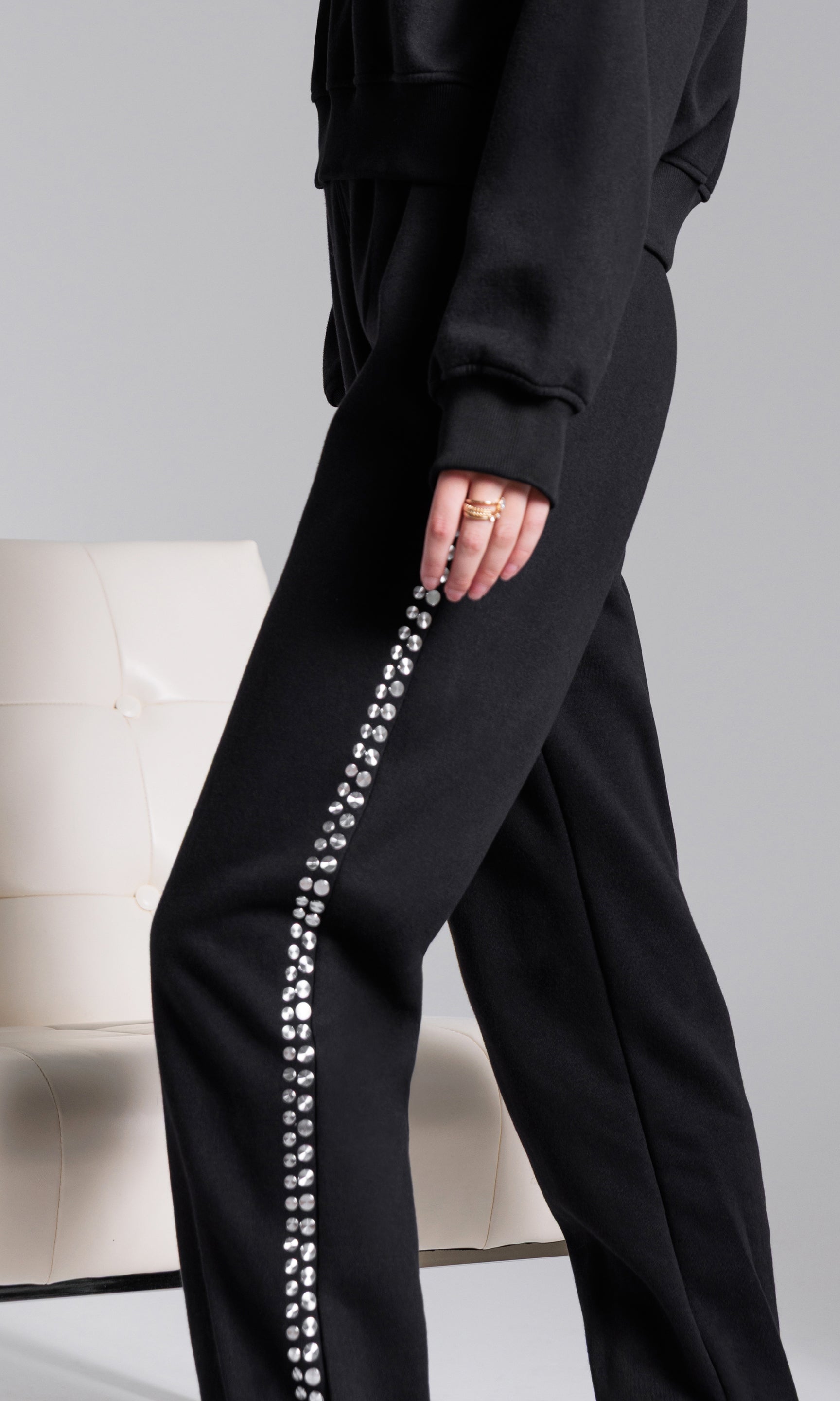 Black pants with a decorative side stripe on a neutral background