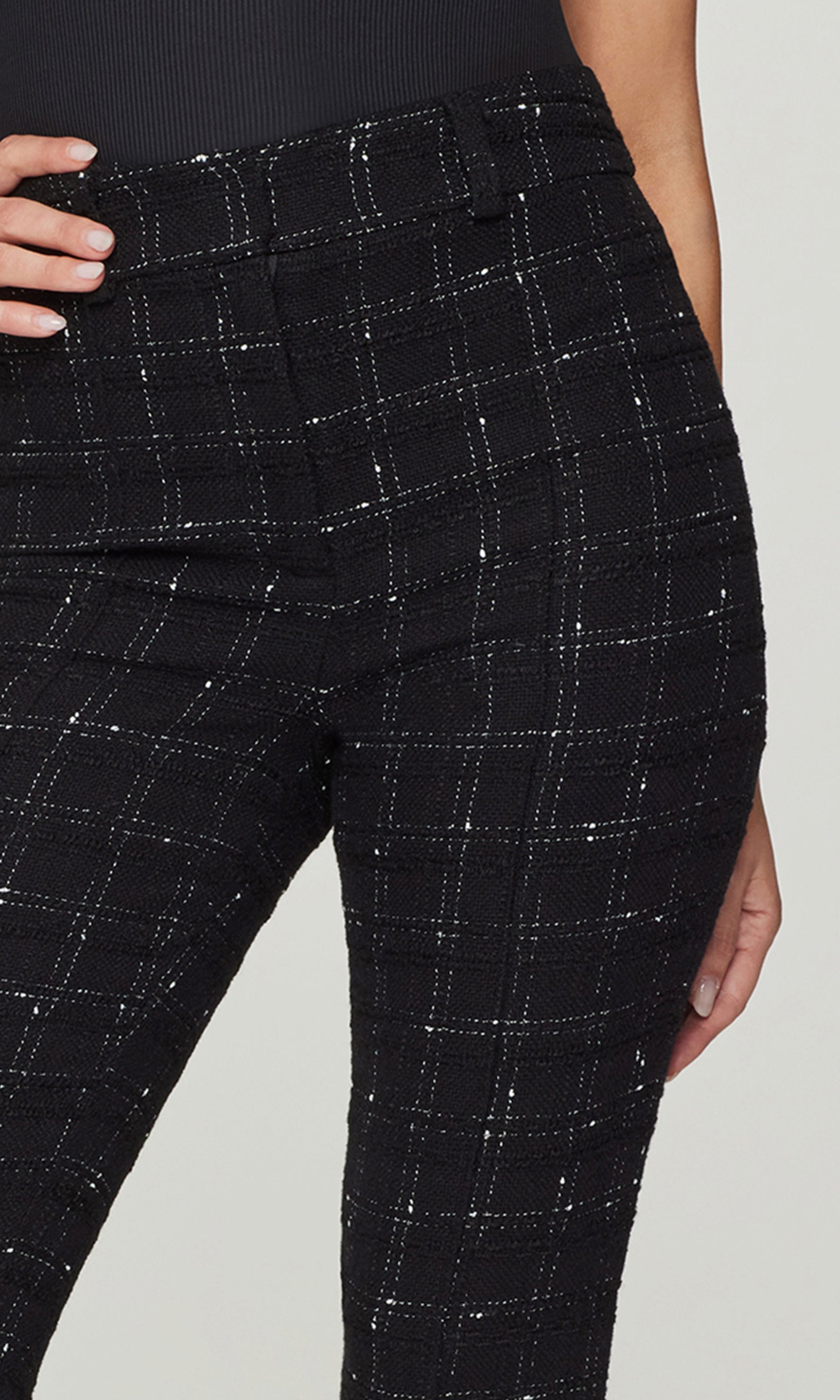 Close-up of black checkered pants worn by a person on a light gray background
