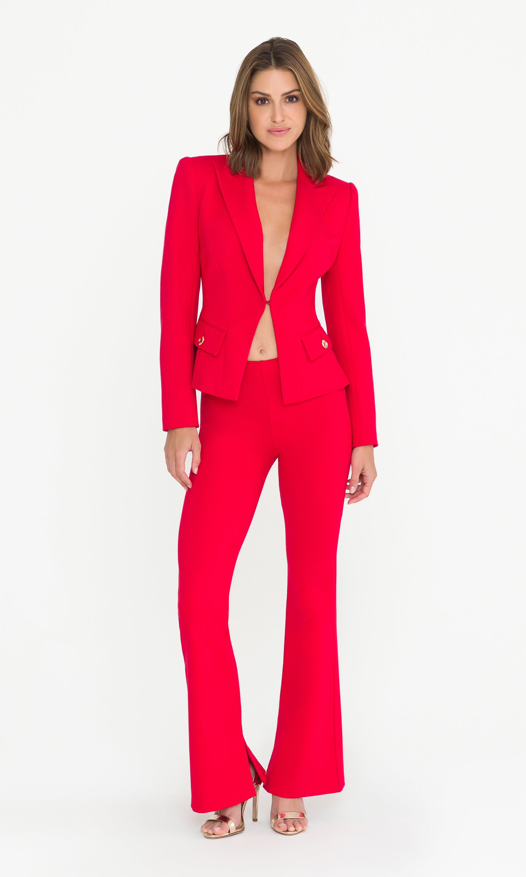 Full body image of model wearing a red suit with gold heels on a white background