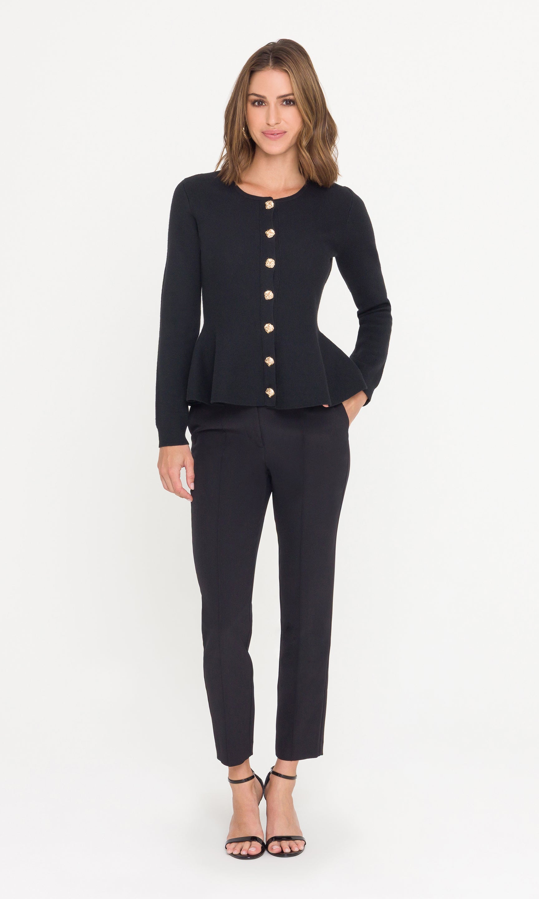Full body image of model wearing a black peplum cardigan and black trousers