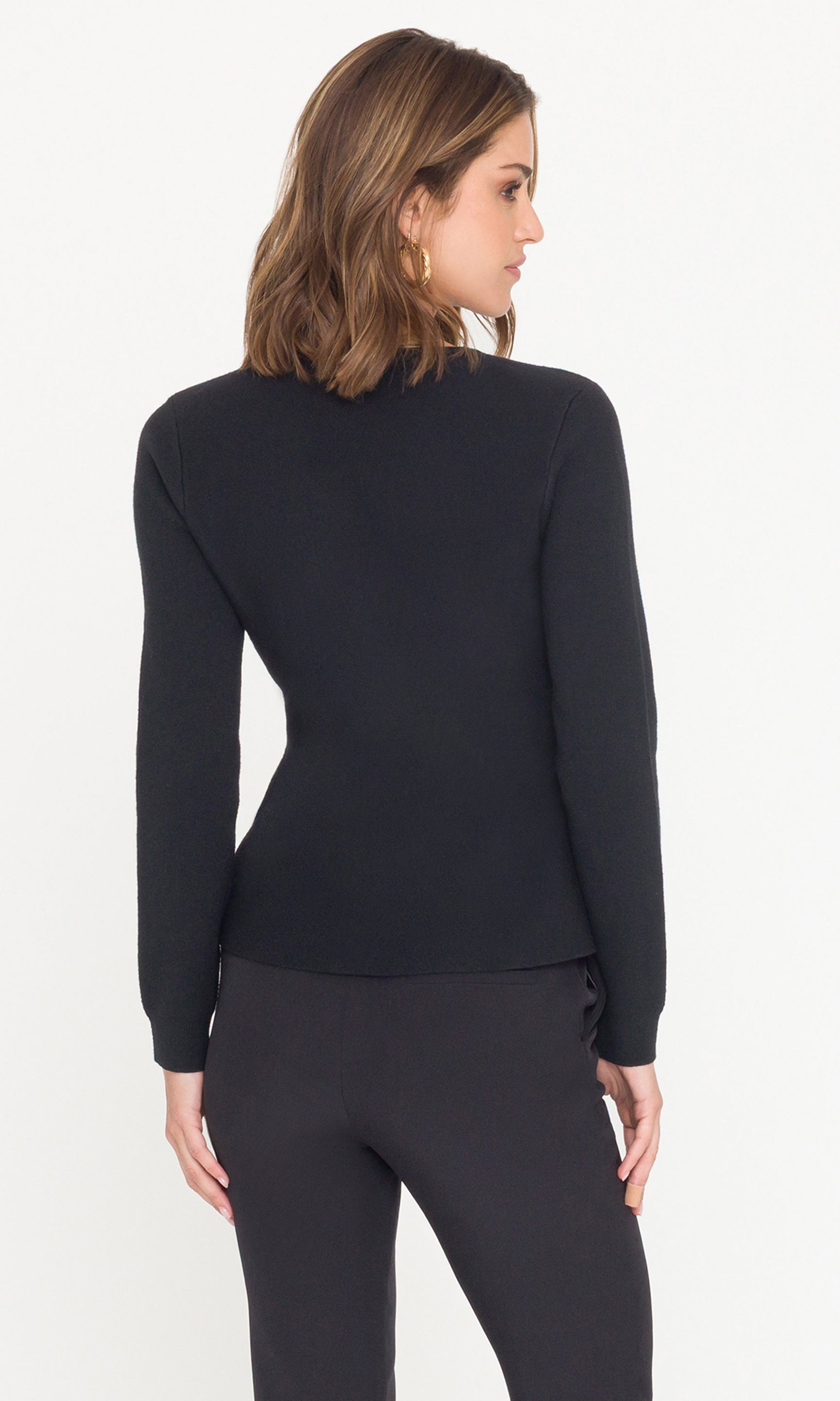 Back view of model wearing a black long-sleeve sweater and pants on a white background