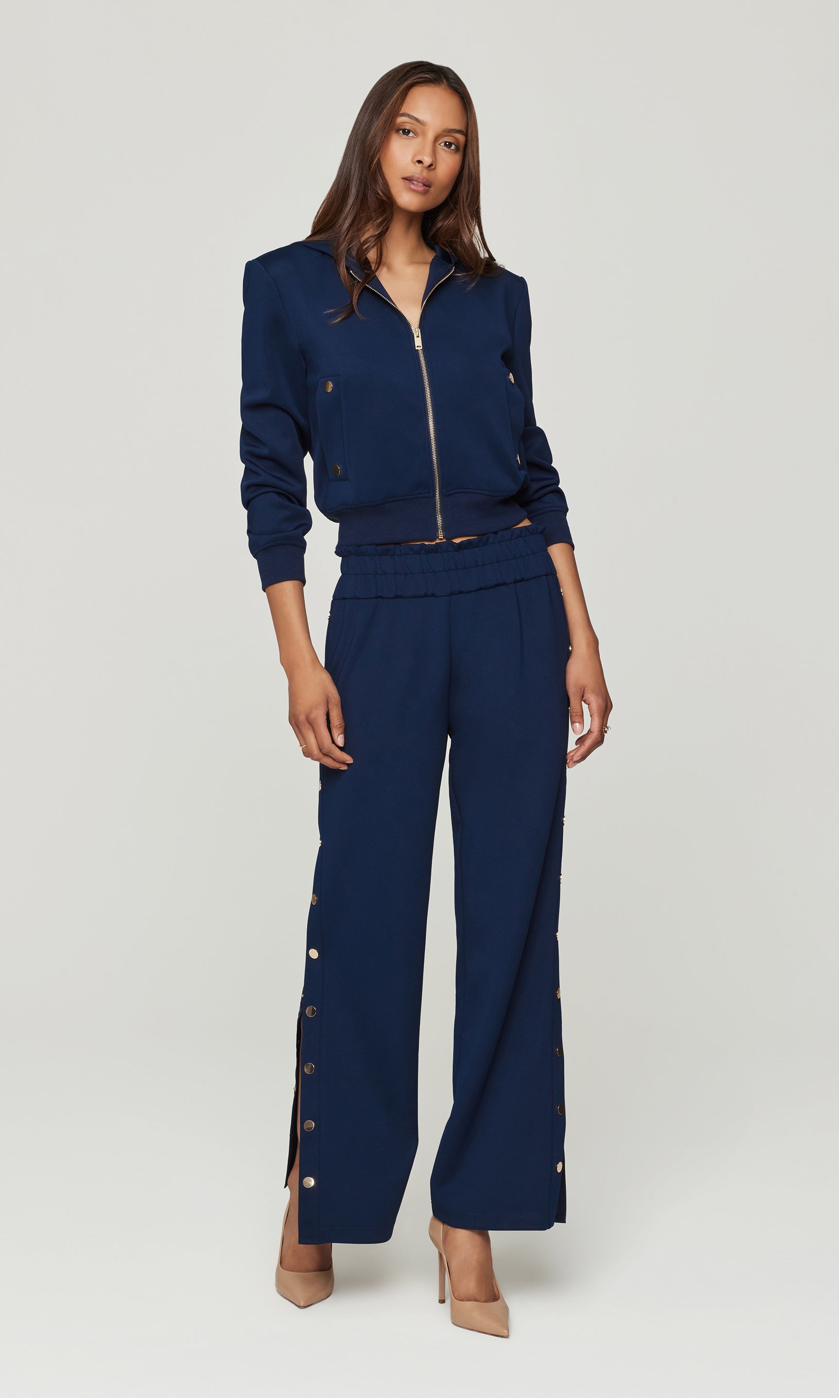 Woman wearing a navy blue outfit with a jacket and pants on a white background