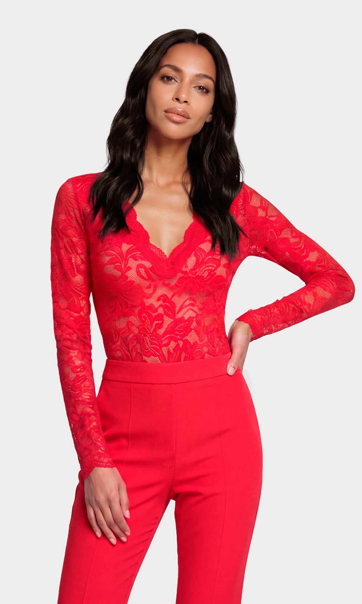 Model wearing a bright red long-sleeve lace top with a V-neckline, paired with matching red high-waisted pants.