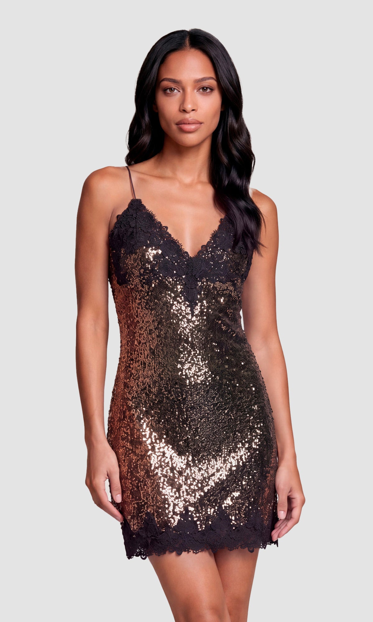 Model wearing a short, sleeveless bronze sequin dress with thin straps and a lace-trimmed V-neckline.