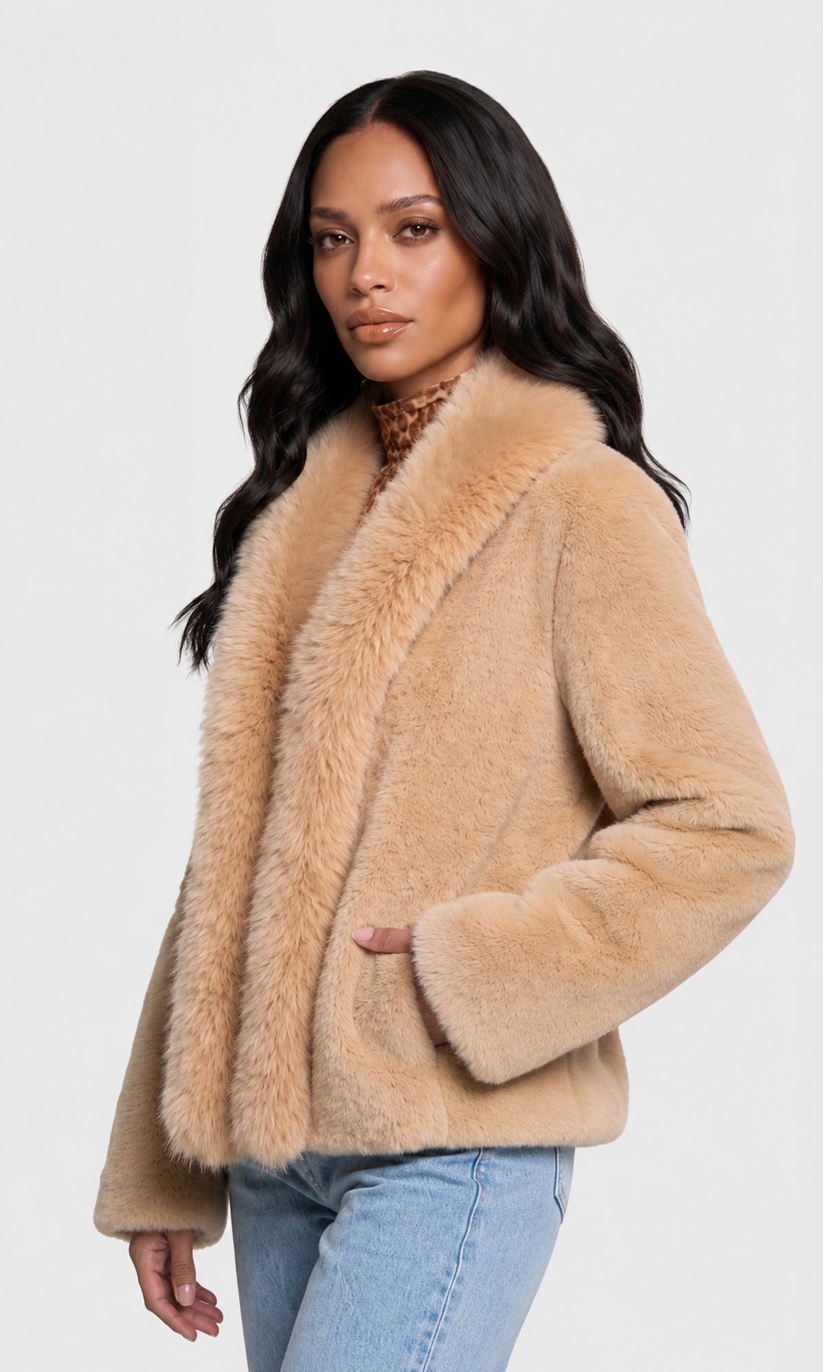 Side view of model wearing a light tan faux fur jacket with a wide collar and long sleeves, paired with light blue jeans.